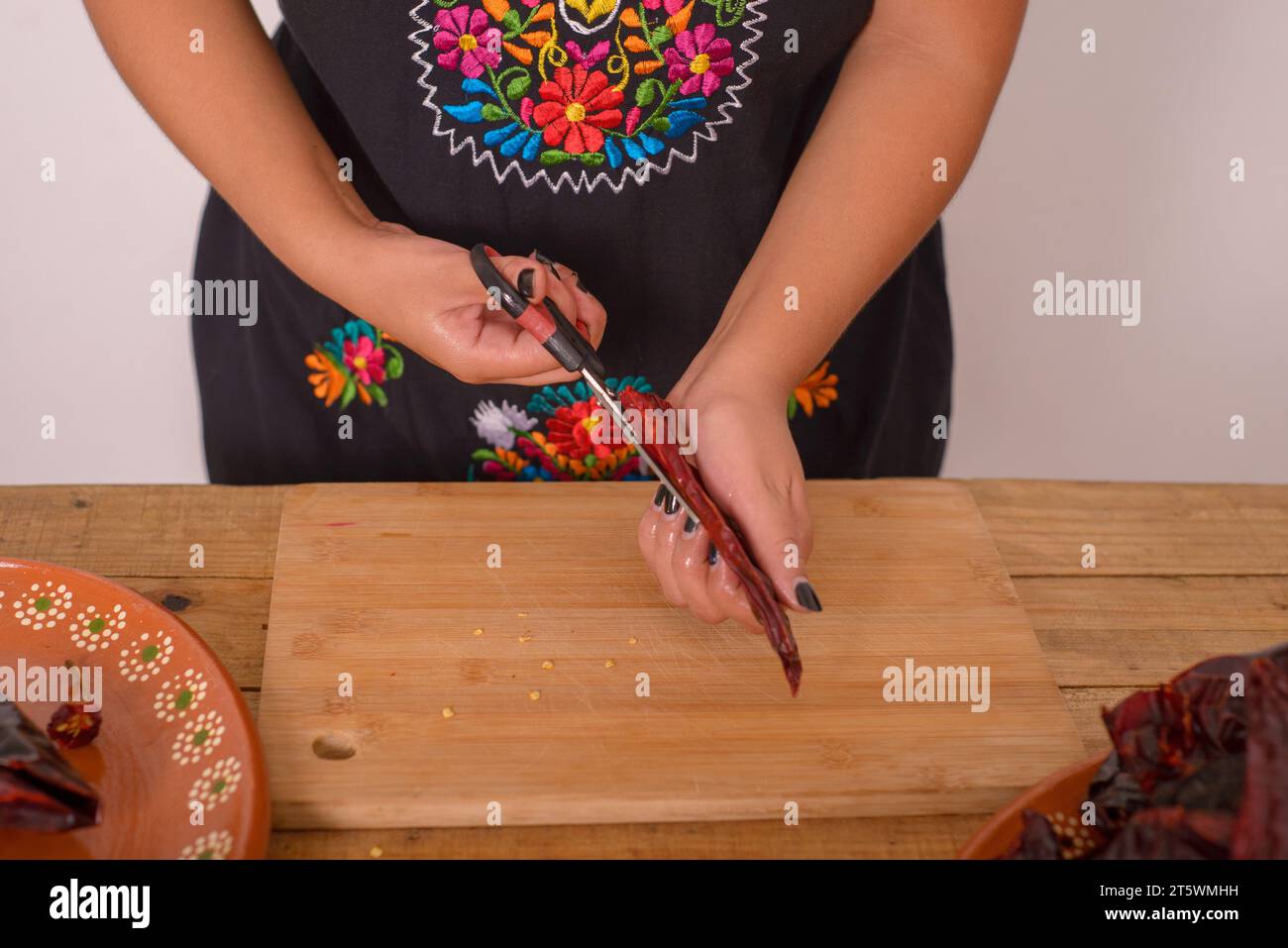 Frau, die Ancho Chili öffnet, um die Samen zu entfernen. Ancho Chili; Gewürze der mexikanischen Küche. Stockfoto