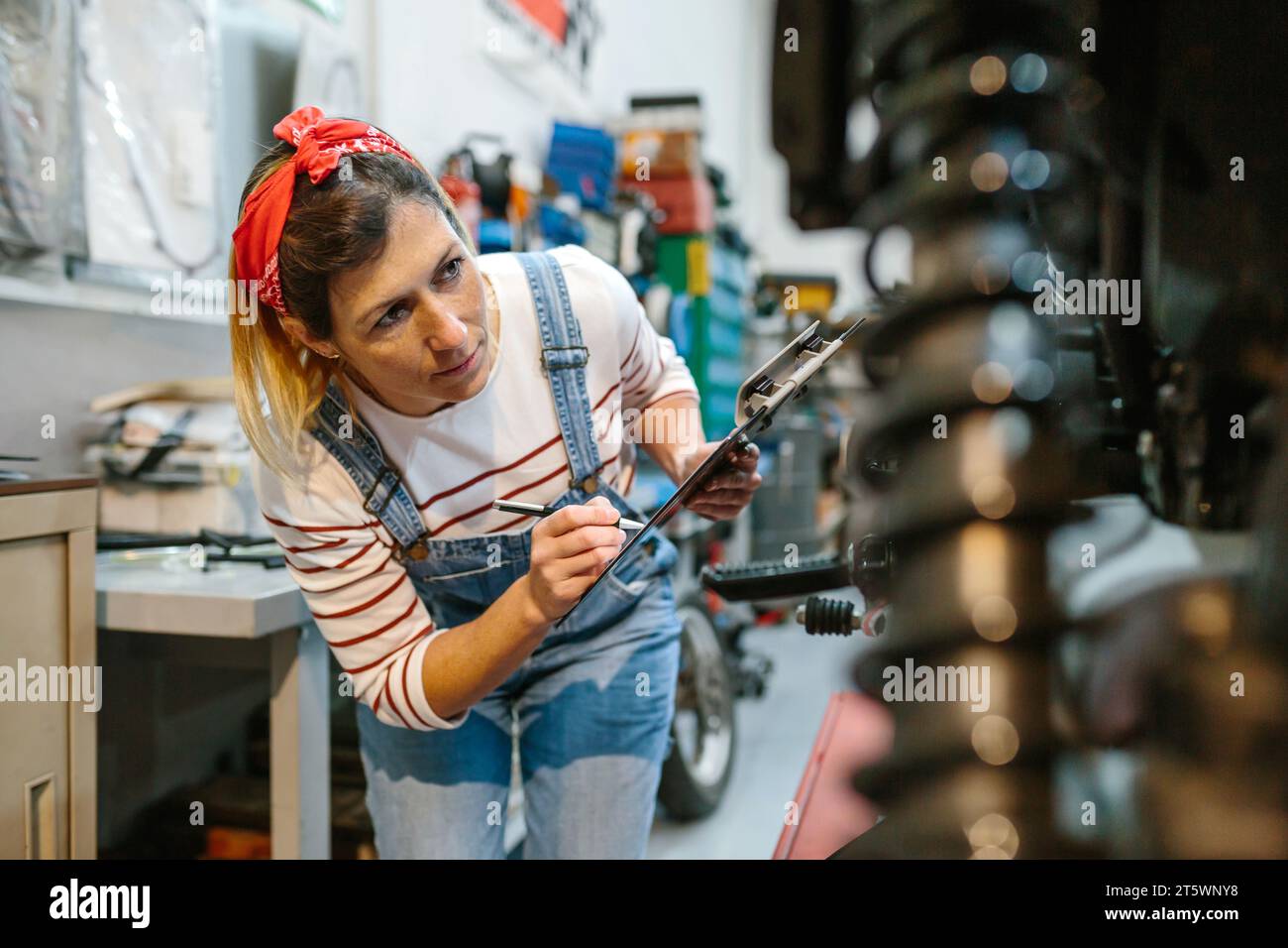 Eine Mechanikerin, die die Motorraddokumentation in der Garage ausfüllt Stockfoto