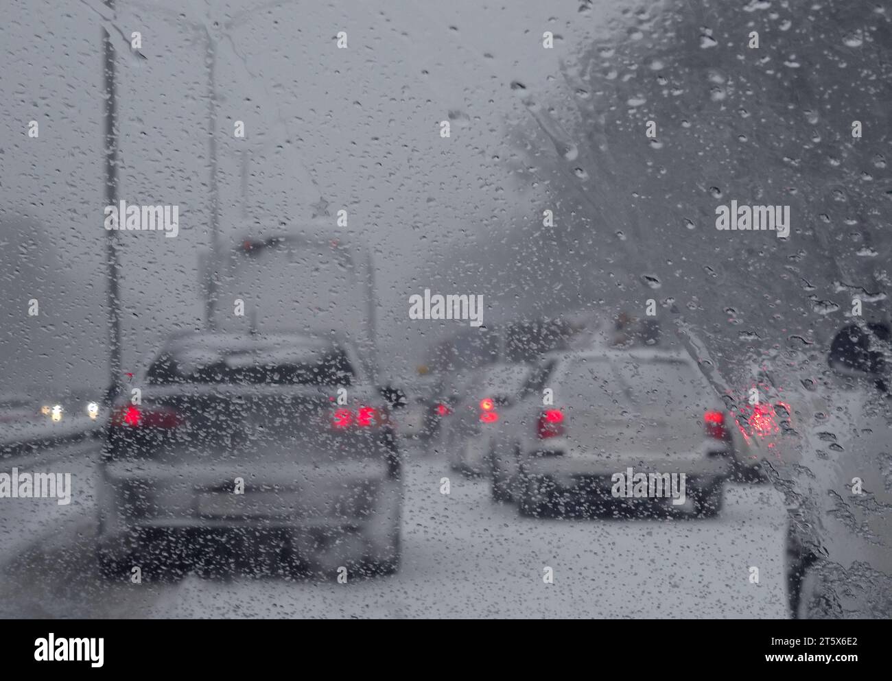 Blick durch die Windschutzscheibe auf die blockierten Fahrzeuge auf der Autobahn bei Schneefall Stockfoto