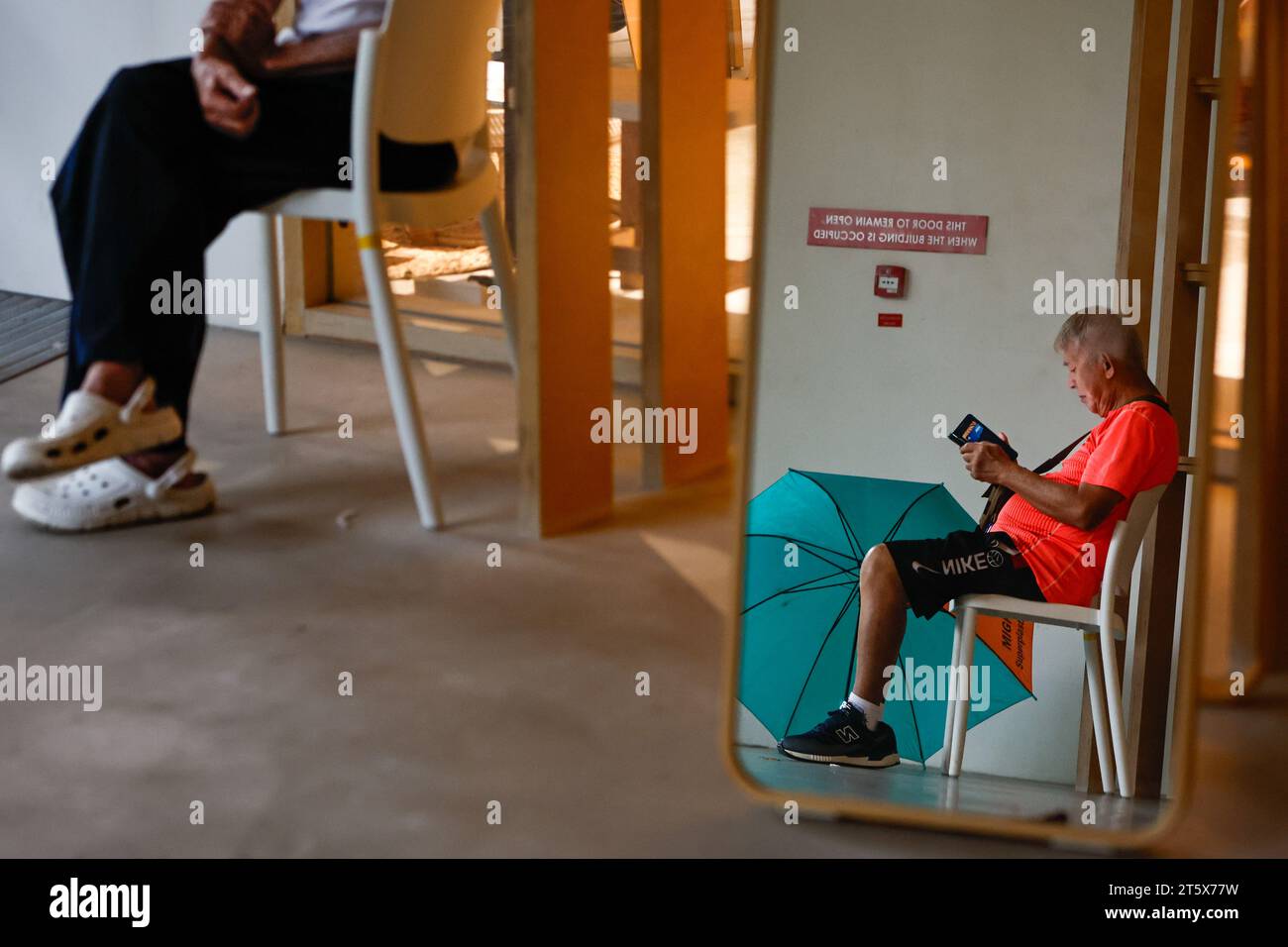 Singapur, Singapur, Singapur. November 2023. Die Einheimischen verstecken sich vor dem heftigen Regen im Humanistischen Jugendzentrum, da es im Oktober bei den höchsten Temperaturen Erholung bietet. Angesichts der globalen Erwärmung und des Klimawandels positioniert sich Singapur als CO2-Drehscheibe Asiens, indem es CO2-Steuern einführt und nachhaltige Energiepolitiken umsetzt und gleichzeitig versucht, den Stadtstaat durch das Pflanzen weiterer Bäume grüner zu machen. (Kreditbild: © Daniel Ceng Shou-Yi/ZUMA Press Wire) NUR REDAKTIONELLE VERWENDUNG! Nicht für kommerzielle ZWECKE! Stockfoto