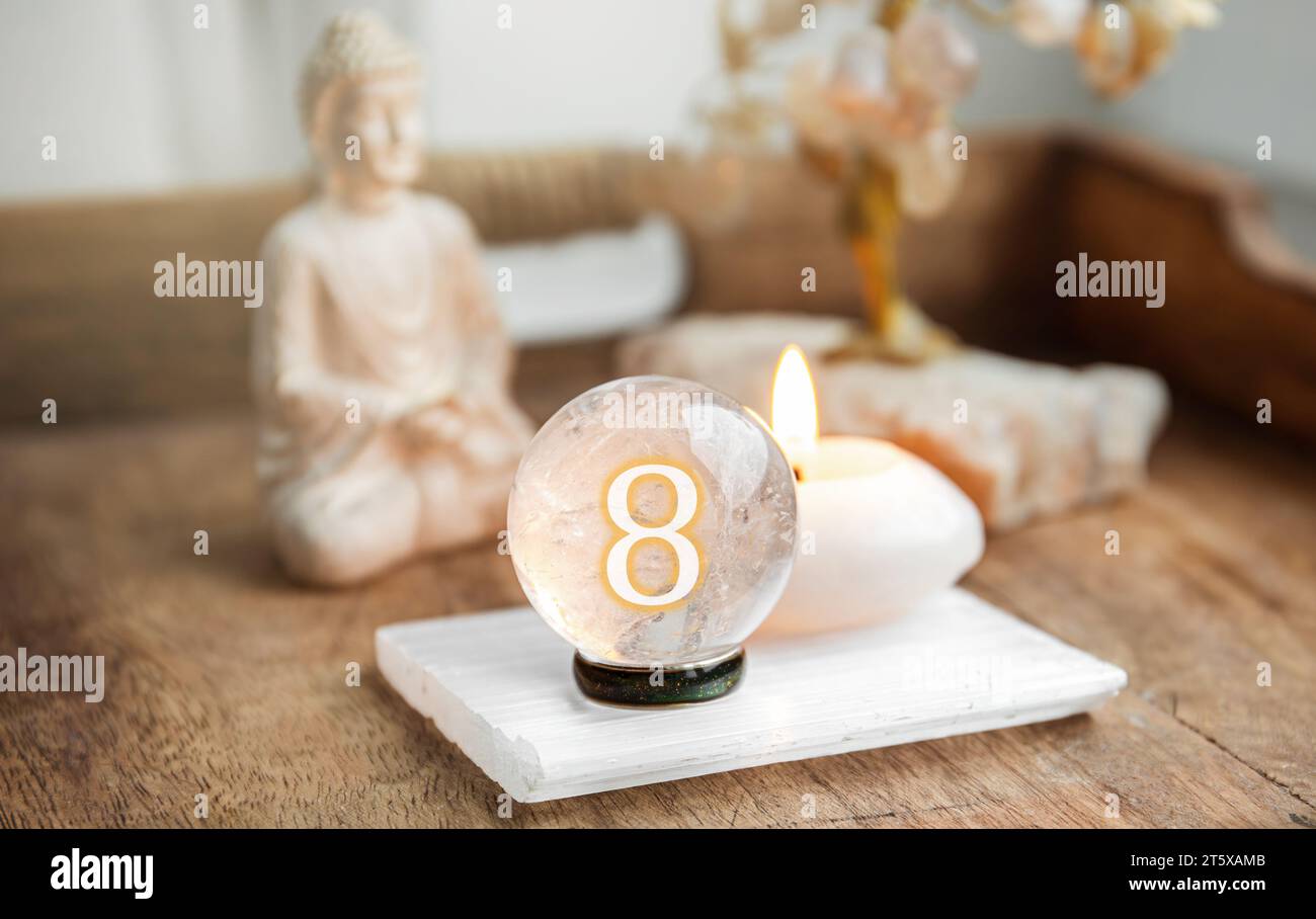 Nummer acht auf der Edelsteinkugel oder Kristallkugeln, bekannt als Kristallum orbis und Orbuculum. Natürliche klare Quarzkugel auf dem Ständer auf Holzschale zu Hause. Stockfoto
