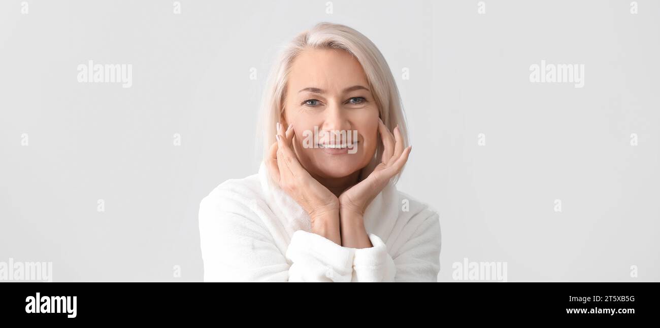 Reife Frau geben sich Massage auf hellen Hintergrund Gesicht Stockfoto