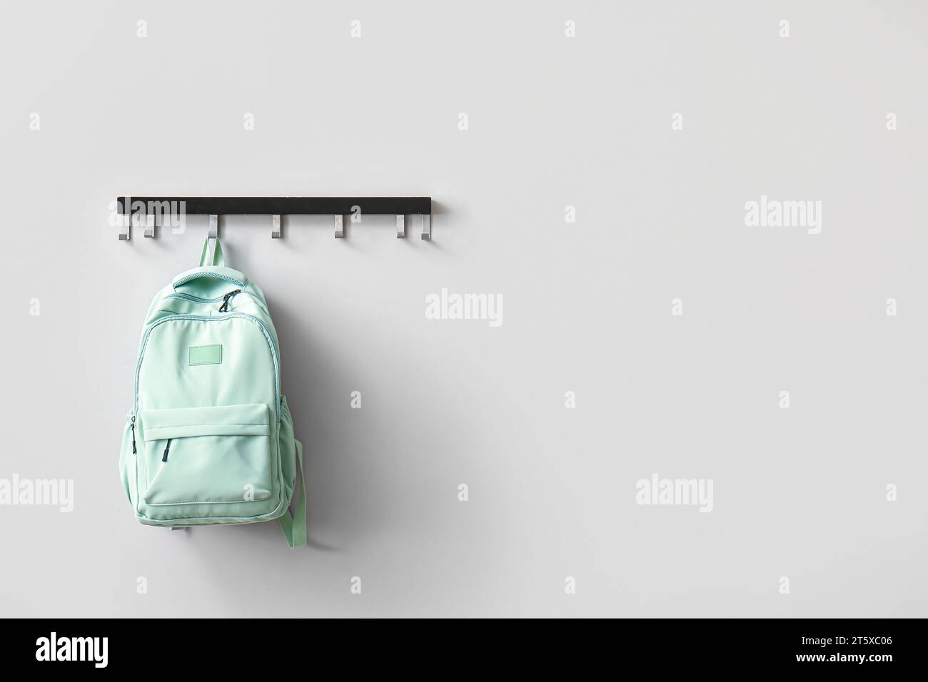 Stilvoller Schulrucksack an weißer Wand im Zimmer Stockfoto
