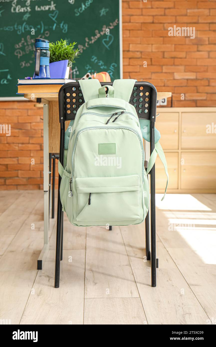 Stilvoller Schulrucksack, der im Klassenzimmer am Stuhl hängt Stockfoto