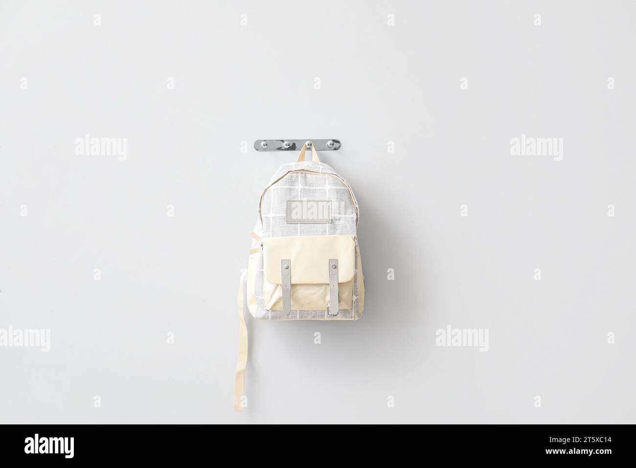 Stylischer Schulrucksack, der an einer hellen Wand hängt Stockfoto