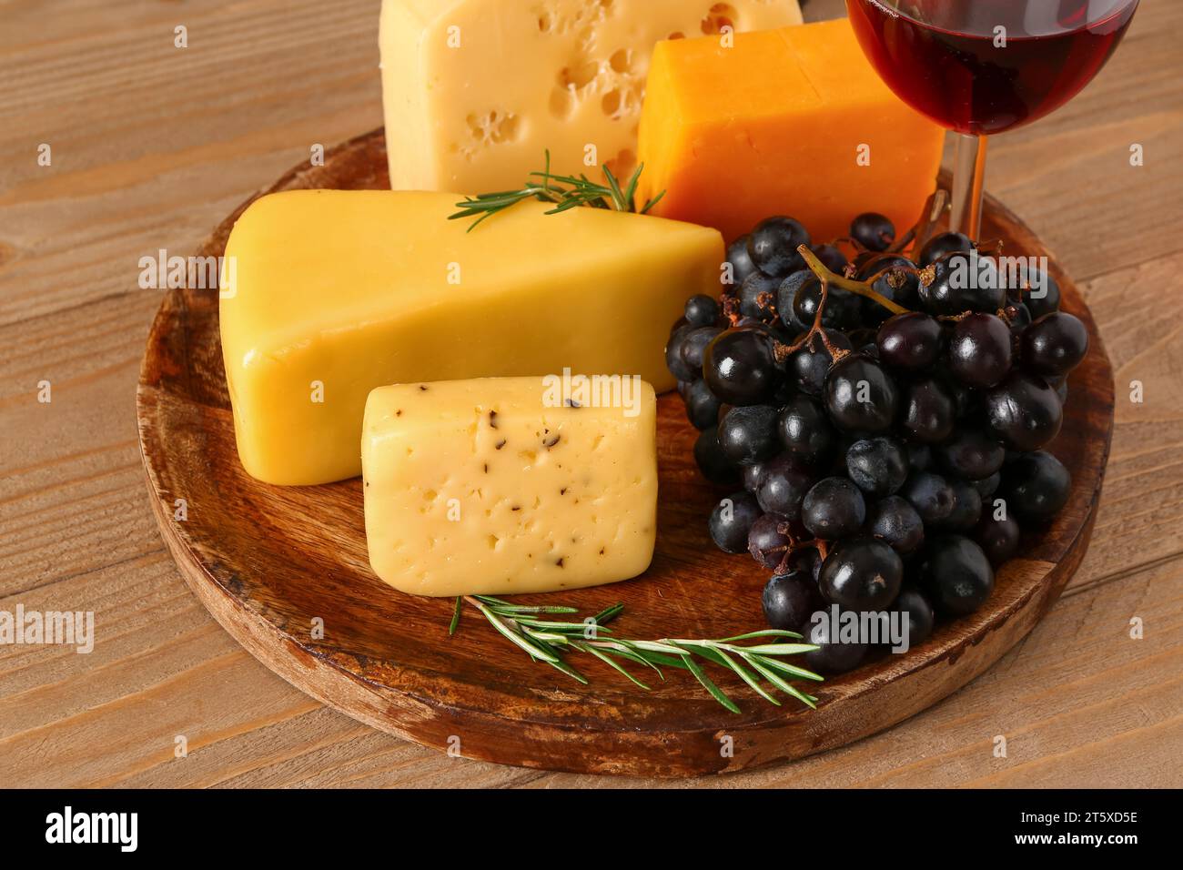 Teller mit leckerem Käse und Trauben auf hölzernem Hintergrund Stockfoto