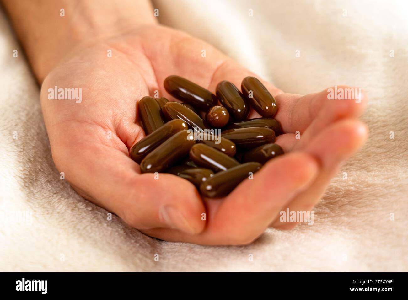 Männliche Hand mit Pillen auf dem Bett. Arzneimittelüberdosiskonzept Stockfoto