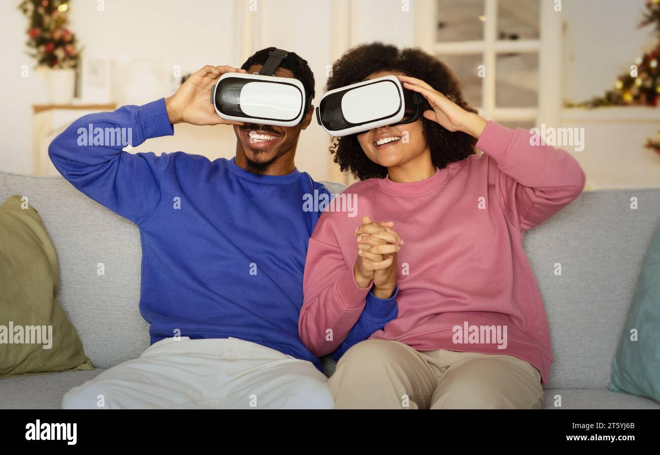 Schwarzes Paar mit VR-Headsets in Innenräumen in die Online-Simulation vertieft Stockfoto