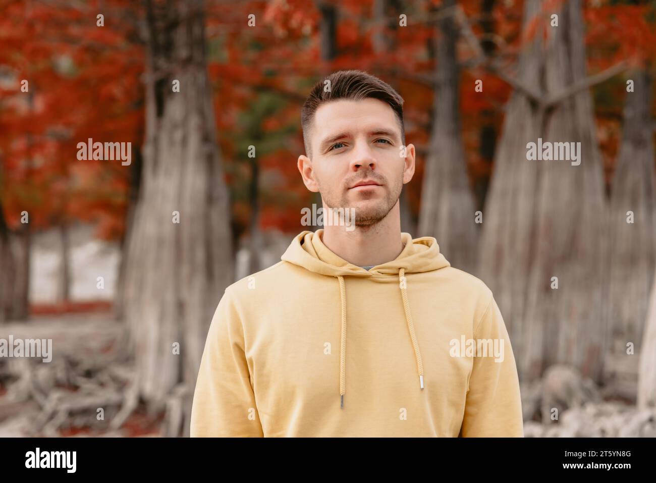 Schöner Mann im herbstlichen Wald. Kaukasier in gelben Kapuzenpullis Stockfoto