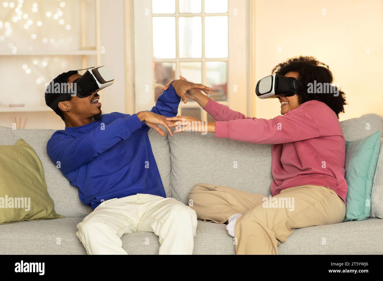 Schwarzes junges Paar, das unterhaltsame und interaktive VR-Simulationen in Innenräumen erlebt Stockfoto