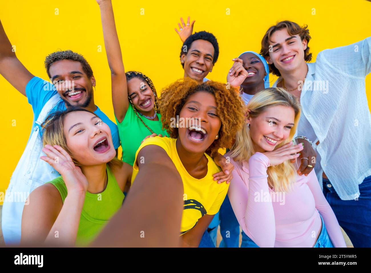Frontalansicht von glücklichen verschiedenen Freunden, die ein Selfie machen, lächelnd und lachend auf gelbem Hintergrund Stockfoto