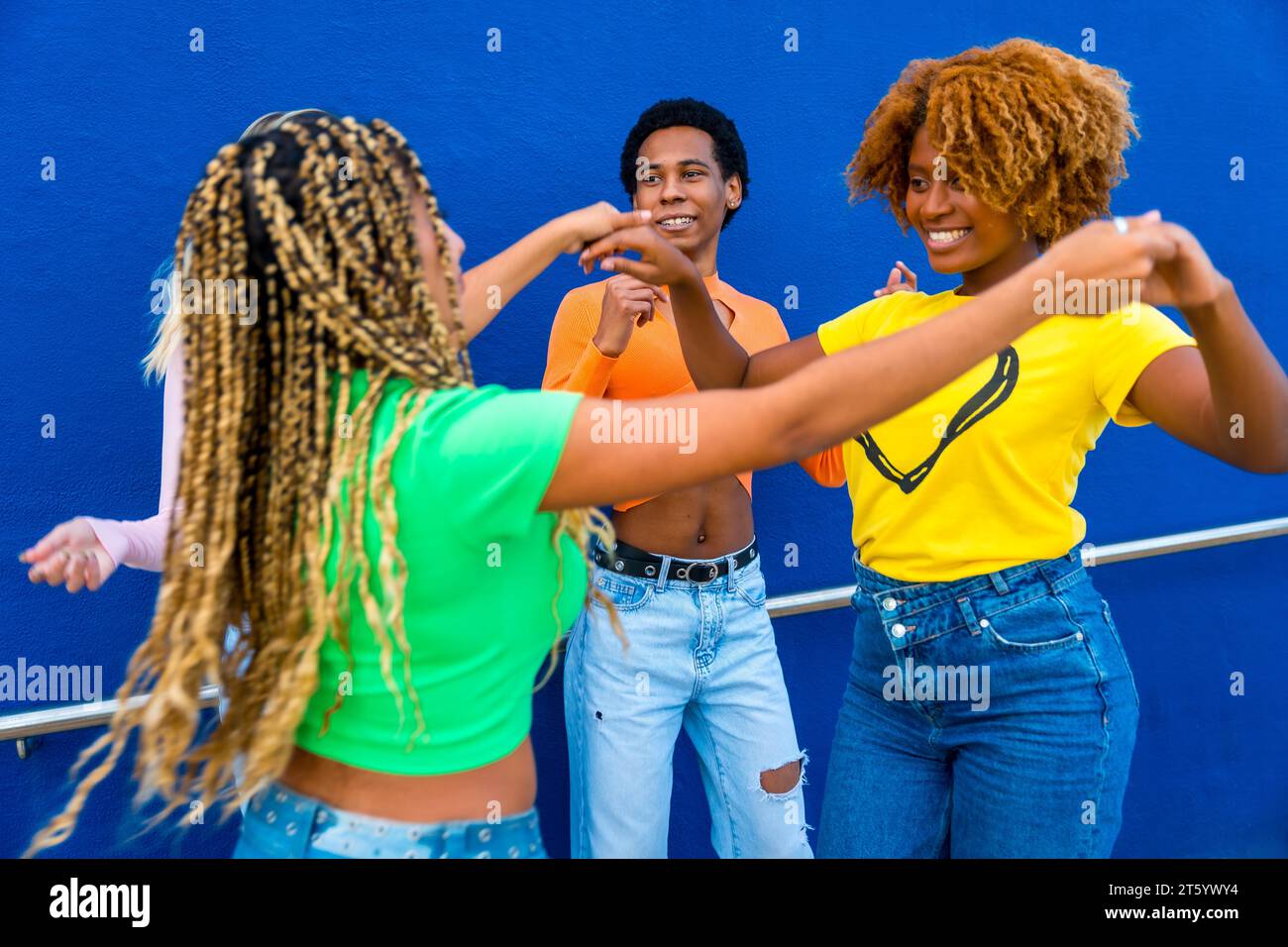 Dynamisches Foto von fröhlichen multirassischen Freunden, die zusammen tanzen und Hände im Freien halten Stockfoto