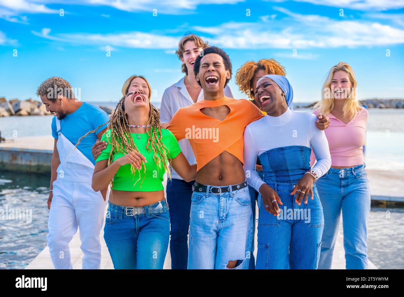 Frontalansicht von fröhlichen, multiethnischen Freunden, die Spaß beim gemeinsamen Spaziergang am Meer haben Stockfoto