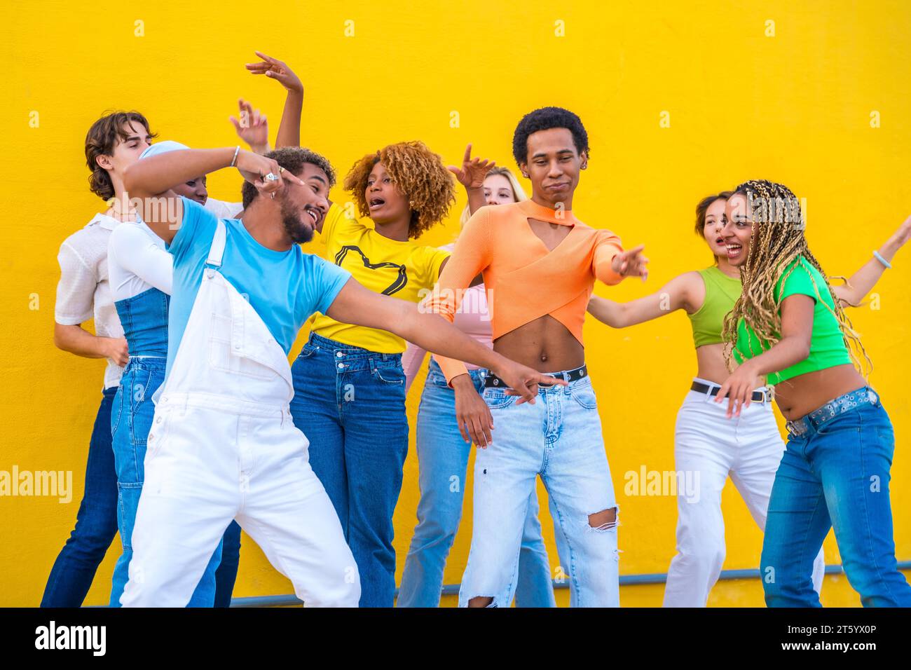 Multikulturelle Gruppe glücklicher Jugendlicher, die in einem gelben städtischen Raum zusammen tanzen Stockfoto