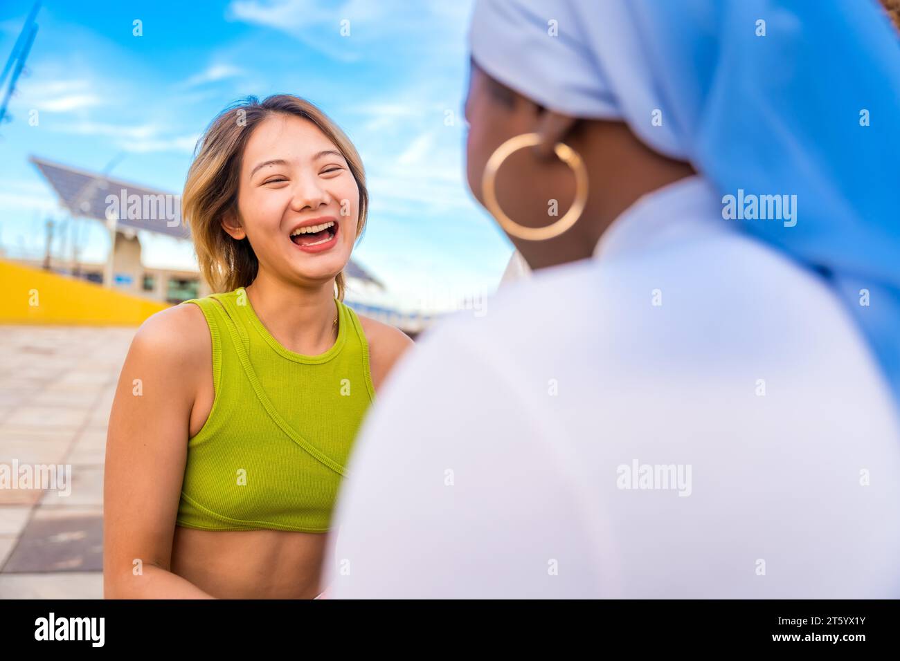 Eine junge und lächelnde chinesin, die sich draußen mit Freunden unterhalten kann Stockfoto