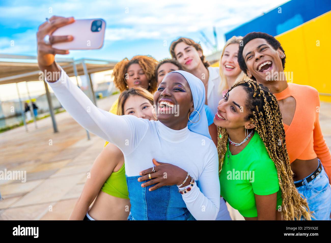 Glückliche muslimische afrikanerin, die ein Selfie macht, während sie mit Freunden lacht Stockfoto