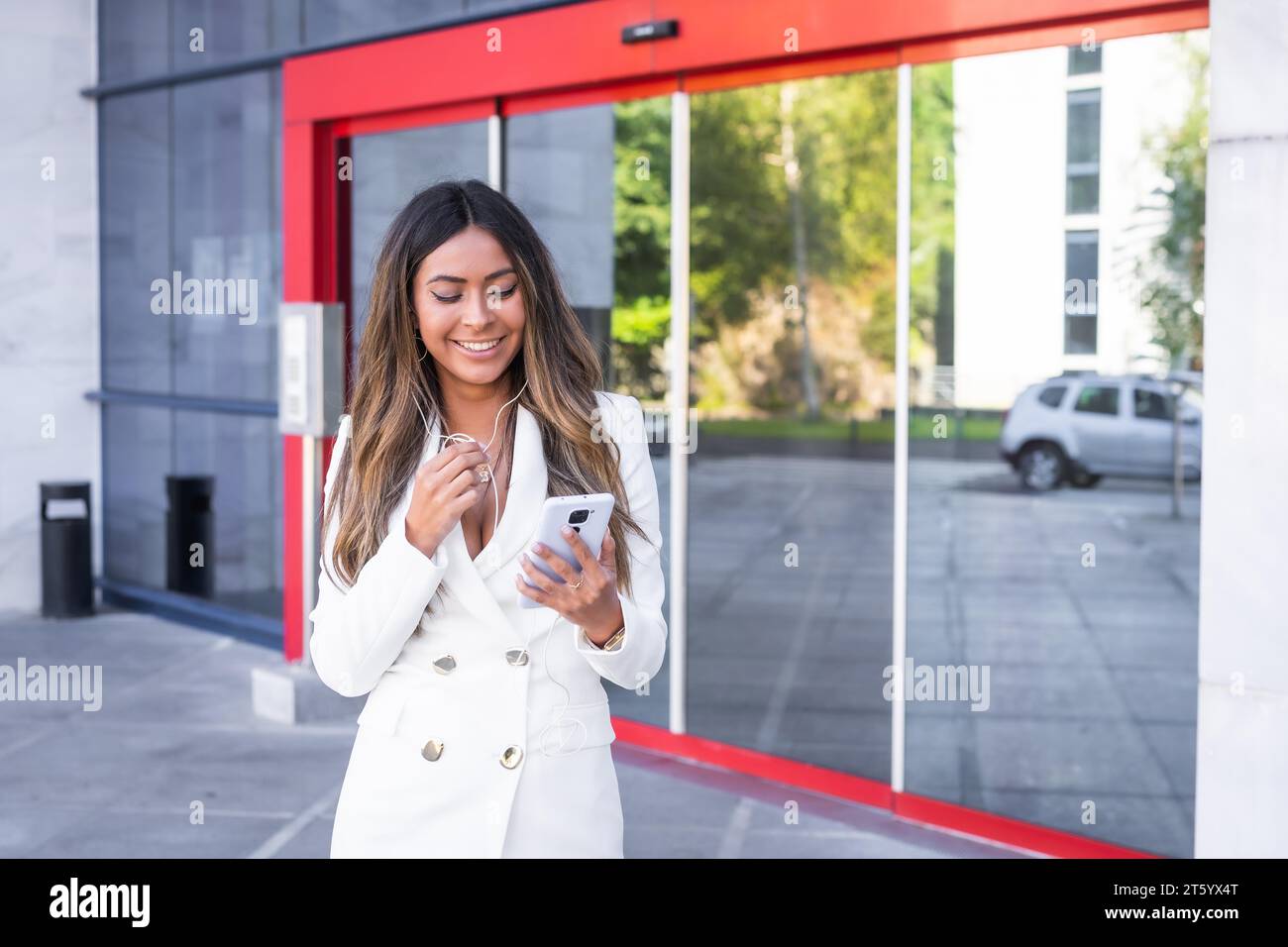 Geschäftsfrau benutzt Handy während einer Videokonferenz vor einem Finanzgebäude Stockfoto
