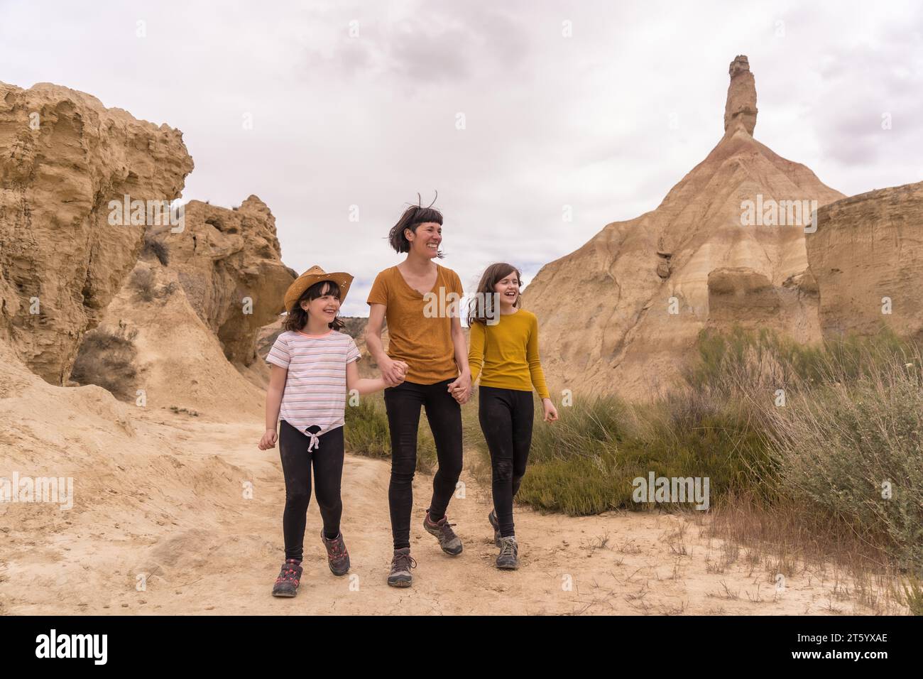 Horizontales Foto mit Kopierraum einer Mutter und einer Tochter, die zusammen in der Wüste spazieren Stockfoto