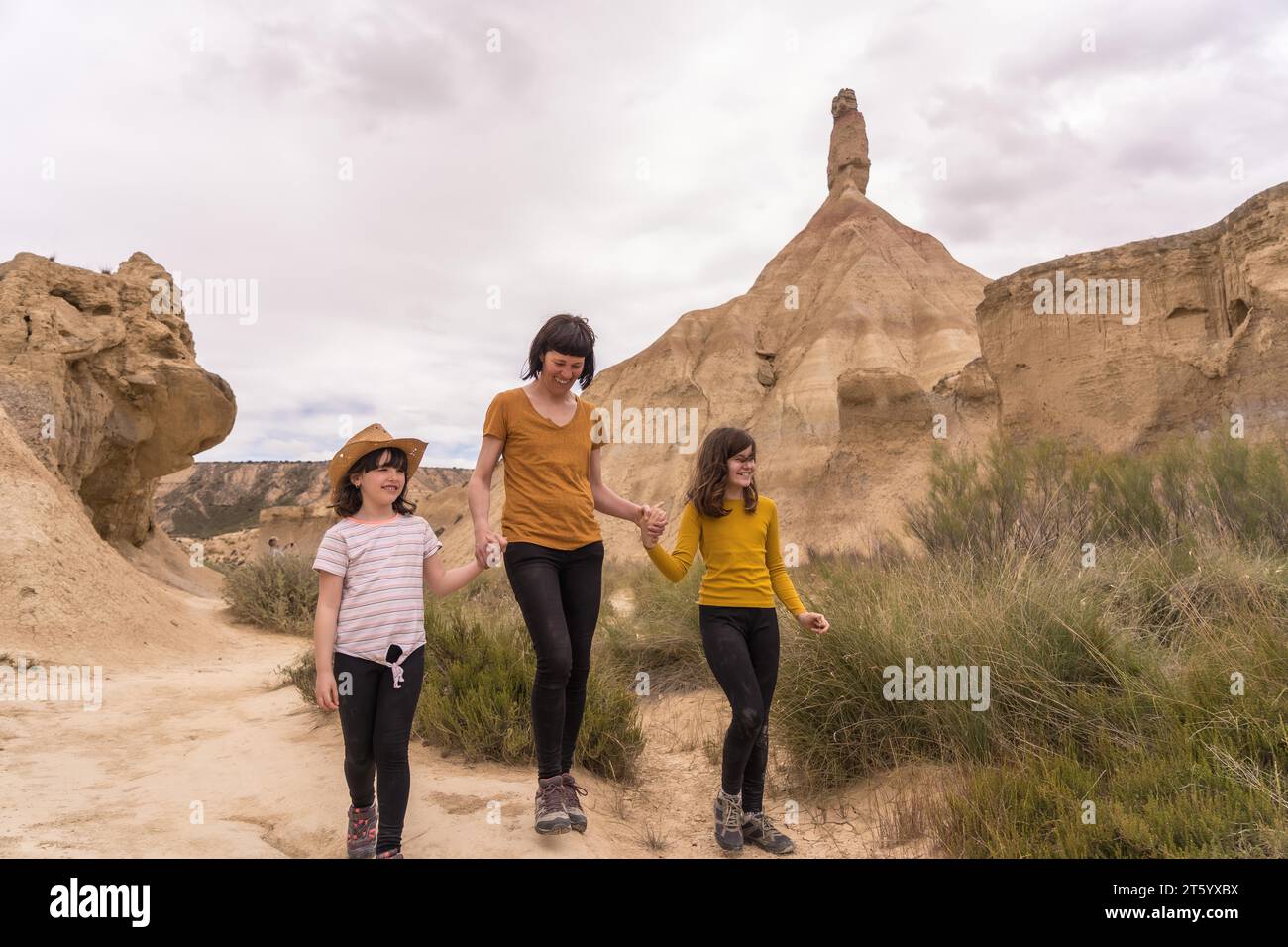 Foto mit Kopierraum einer Mutter mit zwei Kindern, die einen Pfad in einer Wüste entlang laufen Stockfoto