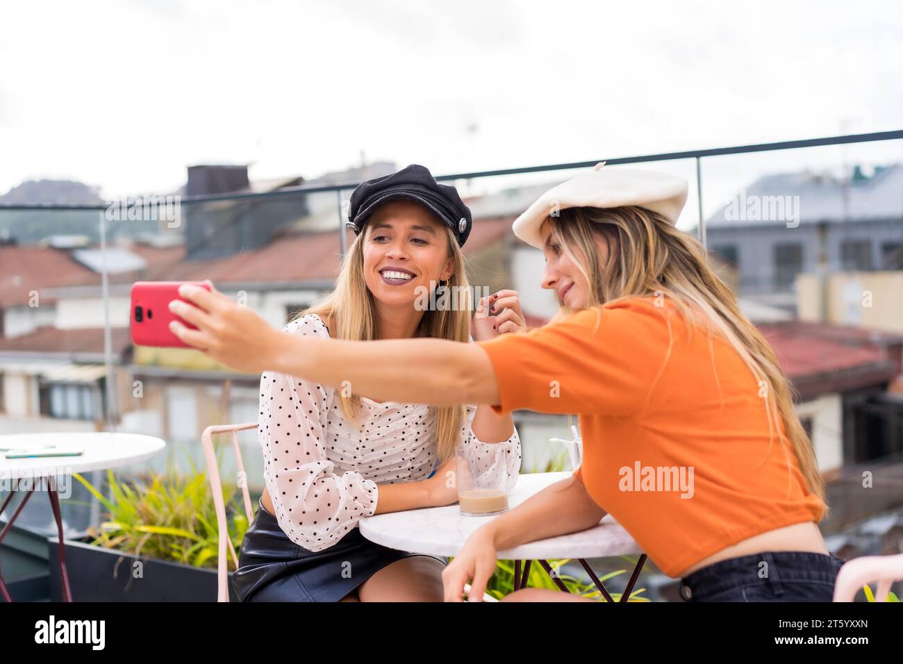 Freunde, die ein Selfie mit dem Handy machen, in einer Cafeteria im Freien mit Blick auf die Stadt Stockfoto