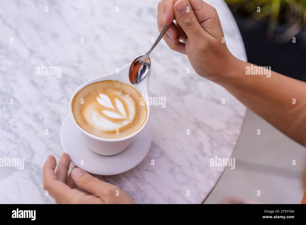 Blick von oben auf eine Frau, die gerade eine perfekte Kaffeetasse auf einer Außenterrasse trinken wird Stockfoto