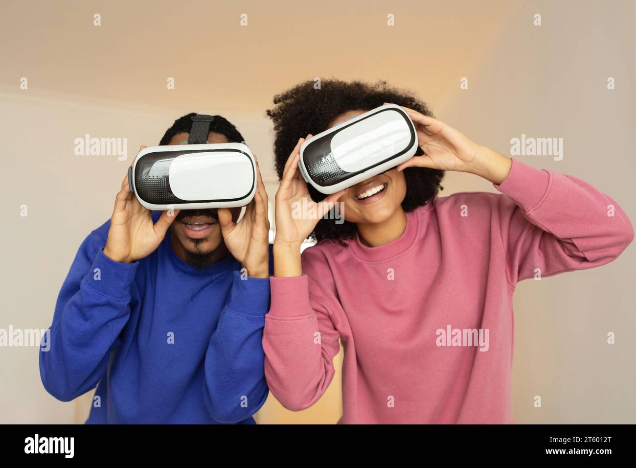 Afroamerikanisches Paar posiert mit einer VR-Brille gegen die Studiowand Stockfoto