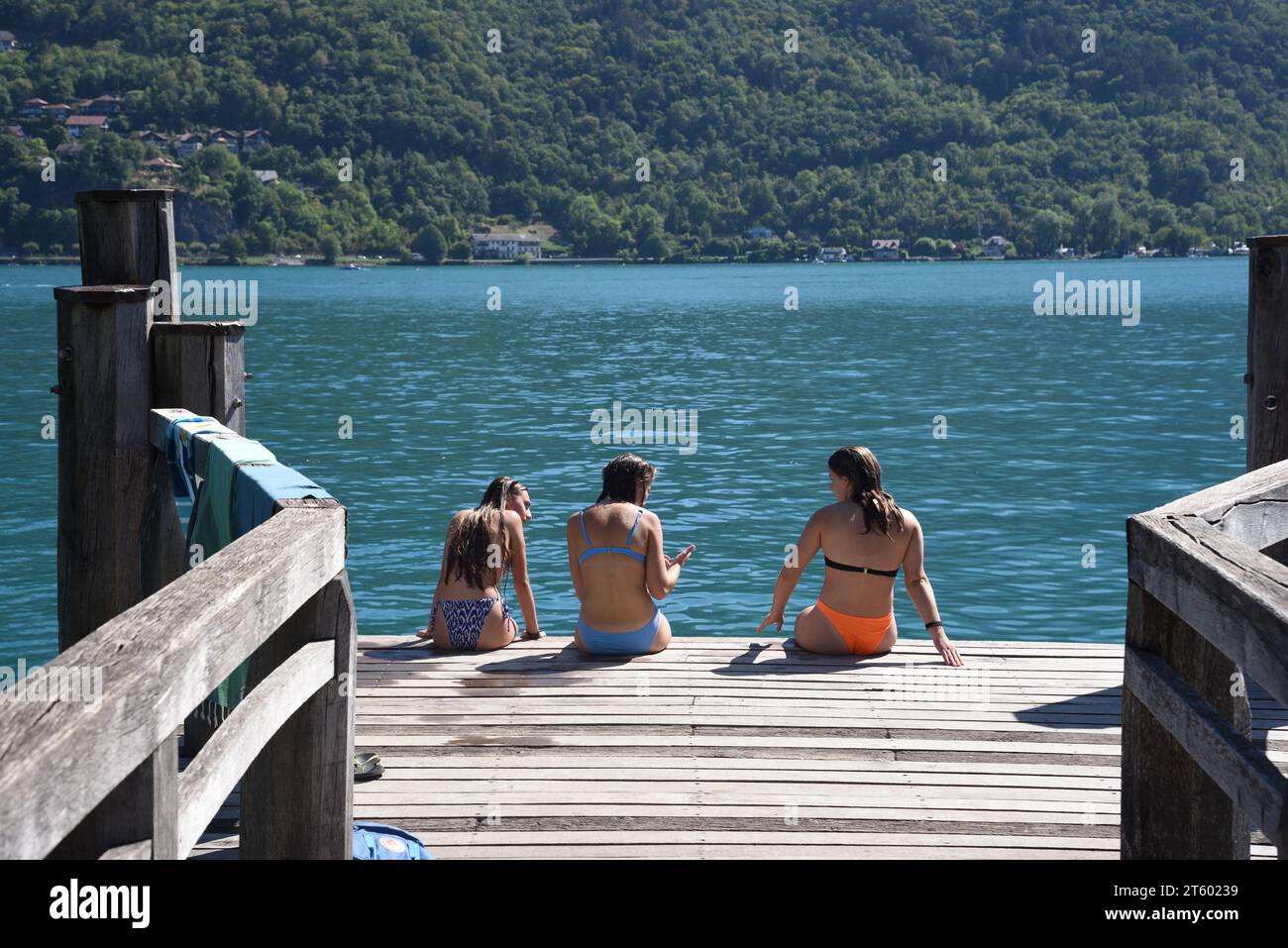 Drei Mädchen, Touristen oder Badende, die Bikinis auf dem Holzsteg Duingt am Lac d'Annecy oder dem See Haute-Savoie in Annecy tragen Stockfoto