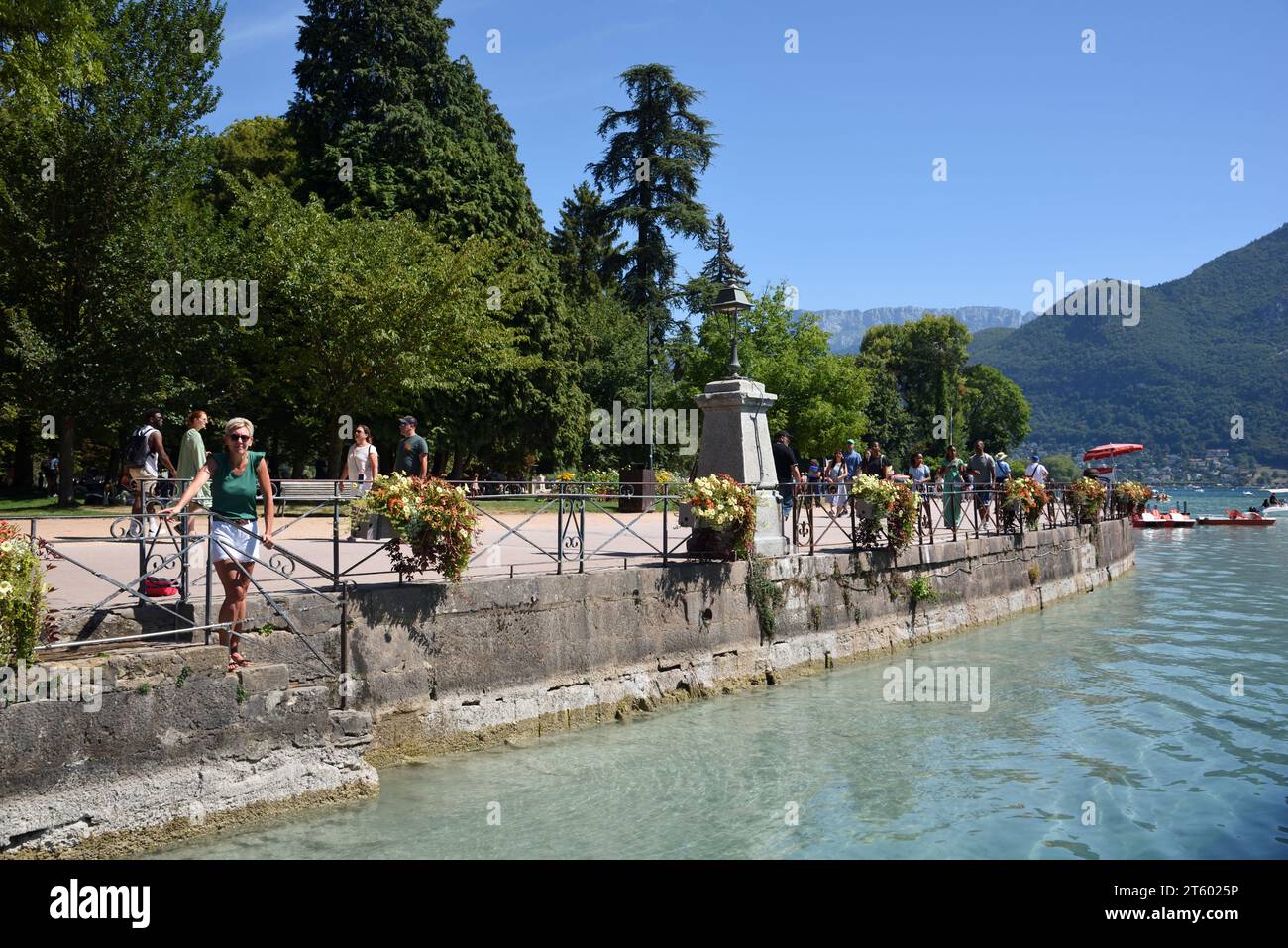 Touristen, die entlang des Quai Napoléon im Jardins de l'Europe am See oder am Ufer des Annecy Lake Annecy Haute-Savoie Frankreich spazieren Stockfoto