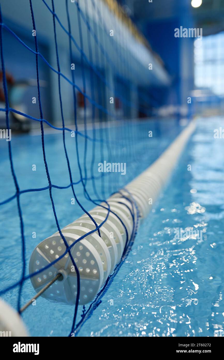 Niedriger Teil des langen Tors mit Netz, das sich über die Oberfläche des reinen blauen Wassers des Schwimmbades erstreckt, das für das Wasserpolo-Training oder -Spiel vorbereitet ist Stockfoto