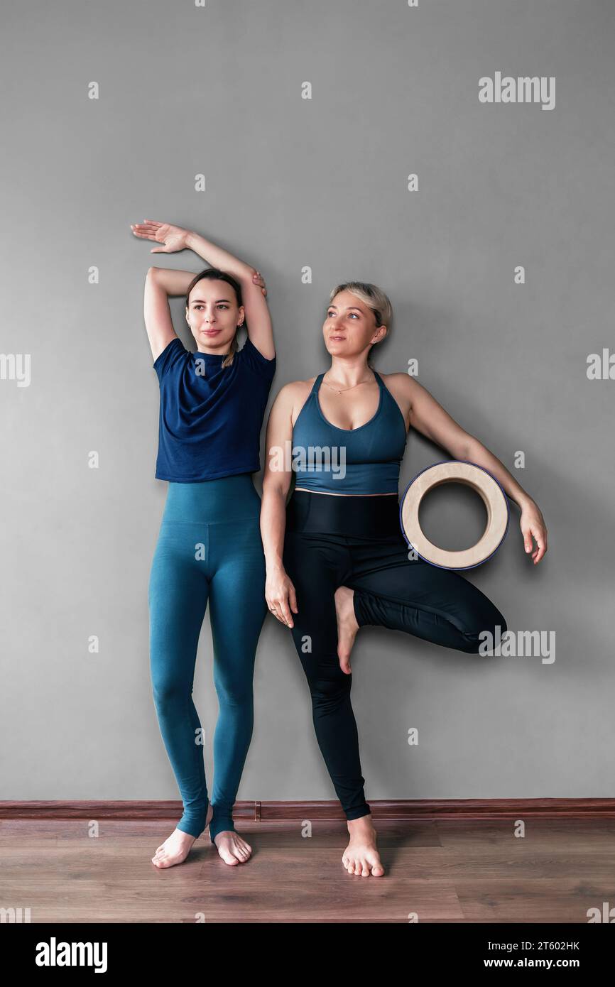Überfröhliche, lange weibliche Yoga-Turnschuhe in Sportbekleidung stehen barfuß in der Nähe der Wand, man hält einen Holzkreis in der Hand und freut sich zu Beginn Stockfoto