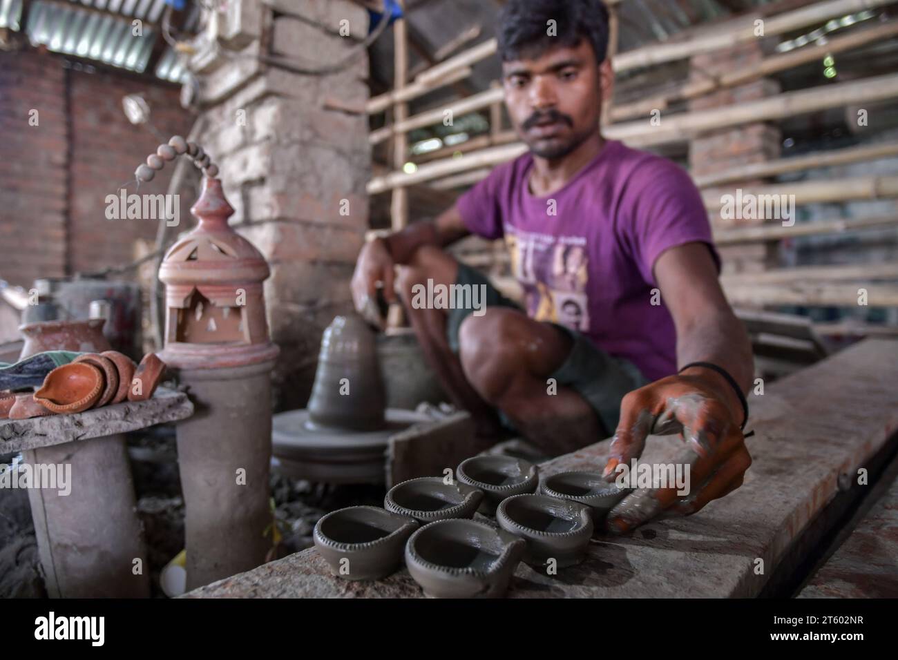 Ein Arbeiter fertigt Erdlampen in dem Töpferdorf Chaltaberia, rund 40 km von Kalkutta in Westbengalen. Das ganze Dorf ist im vollen Rhythmus der irdenen Lampen- und Idol-Produktion vor dem Diwali-Festival in Indien. Erdlampen werden in allen indischen Städten verkauft, wie Kalkutta, Delhi, Mumbai, Hyderabad, Gujarat, Assam, Patna und Rajasthan, besonders während der Festivalsaison. Sogar Erdlampen werden vor den Diwali-Feiern nach außerhalb Indiens exportiert. Stockfoto