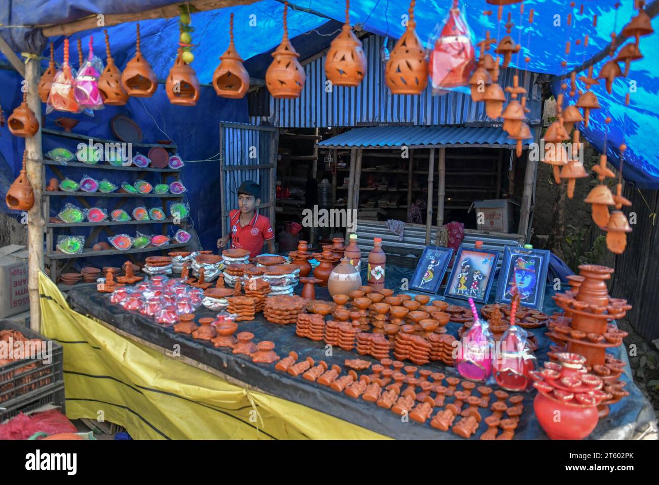 Ein Junge verkauft Erdlampen im Töpferdorf Chaltaberia, rund 40 km von Kalkutta in Westbengalen. Das ganze Dorf ist im vollen Rhythmus der irdenen Lampen- und Idol-Produktion vor dem Diwali-Festival in Indien. Erdlampen werden in allen indischen Städten verkauft, wie Kalkutta, Delhi, Mumbai, Hyderabad, Gujarat, Assam, Patna und Rajasthan, besonders während der Festivalsaison. Sogar Erdlampen werden vor den Diwali-Feiern nach außerhalb Indiens exportiert. Stockfoto