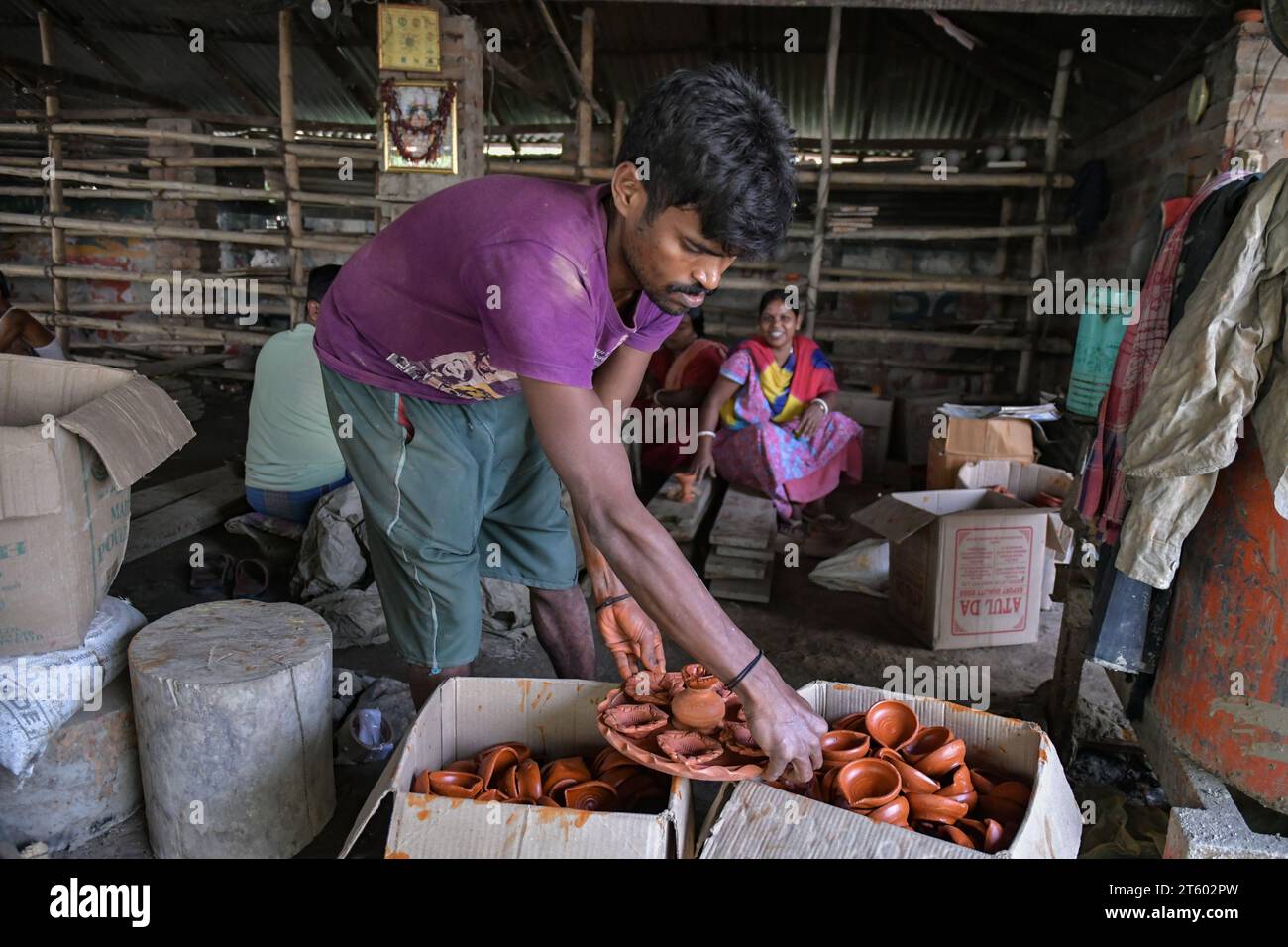 Ein Arbeiter sortiert Erdlampen im Töpferdorf Chaltaberia, rund 40 km von Kalkutta in Westbengalen. Das ganze Dorf ist im vollen Rhythmus der irdenen Lampen- und Idol-Produktion vor dem Diwali-Festival in Indien. Erdlampen werden in allen indischen Städten verkauft, wie Kalkutta, Delhi, Mumbai, Hyderabad, Gujarat, Assam, Patna und Rajasthan, besonders während der Festivalsaison. Sogar Erdlampen werden vor den Diwali-Feiern nach außerhalb Indiens exportiert. Stockfoto