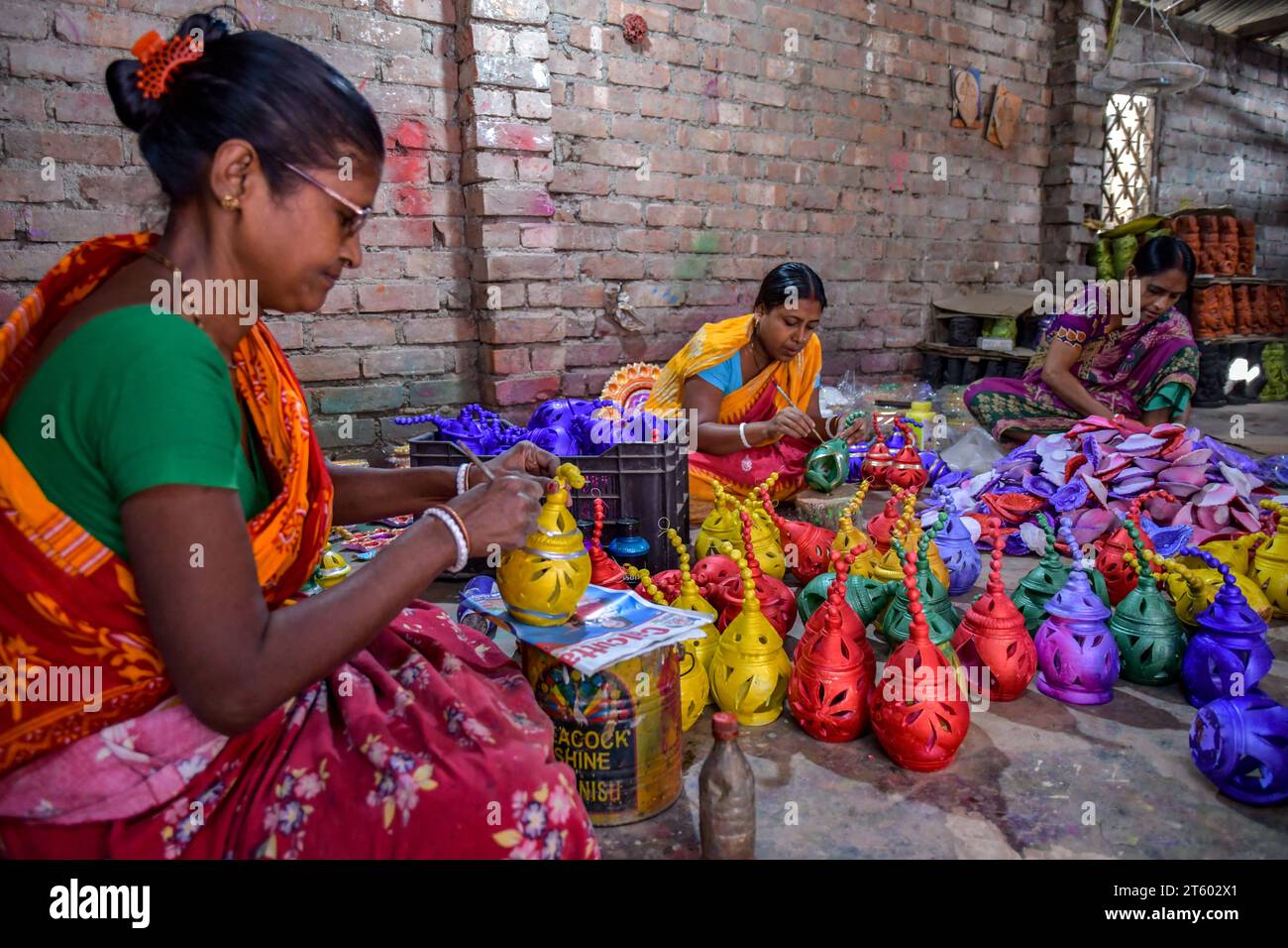 Im Töpferdorf Chaltaberia, rund 40 km von Kalkutta in Westbengalen, färben sich Arbeiterinnen Erdlampen aus. Das ganze Dorf ist im vollen Rhythmus der irdenen Lampen- und Idol-Produktion vor dem Diwali-Festival in Indien. Erdlampen werden in allen indischen Städten verkauft, wie Kalkutta, Delhi, Mumbai, Hyderabad, Gujarat, Assam, Patna und Rajasthan, besonders während der Festivalsaison. Sogar Erdlampen werden vor den Diwali-Feiern nach außerhalb Indiens exportiert. Stockfoto