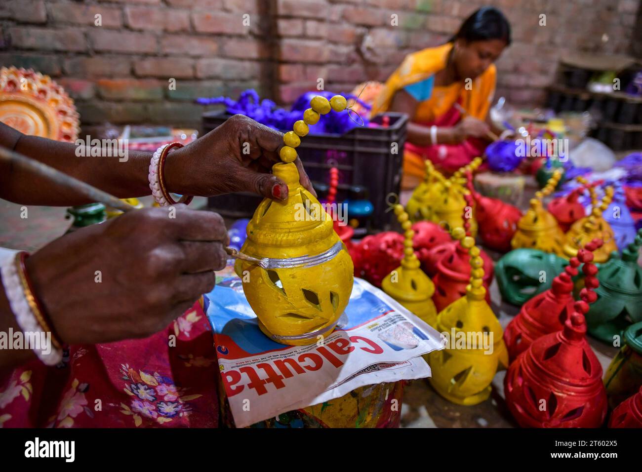 Ein Arbeiter färbt eine Erdlampe in dem Töpferdorf Chaltaberia, rund 40 km vor Kalkutta in Westbengalen. Das ganze Dorf ist im vollen Rhythmus der irdenen Lampen- und Idol-Produktion vor dem Diwali-Festival in Indien. Erdlampen werden in allen indischen Städten verkauft, wie Kalkutta, Delhi, Mumbai, Hyderabad, Gujarat, Assam, Patna und Rajasthan, besonders während der Festivalsaison. Sogar Erdlampen werden vor den Diwali-Feiern nach außerhalb Indiens exportiert. Stockfoto