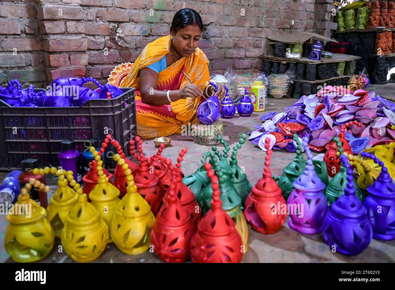 Ein Arbeiter färbt eine Erdlampe in dem Töpferdorf Chaltaberia, rund 40 km vor Kalkutta in Westbengalen. Das ganze Dorf ist im vollen Rhythmus der irdenen Lampen- und Idol-Produktion vor dem Diwali-Festival in Indien. Erdlampen werden in allen indischen Städten verkauft, wie Kalkutta, Delhi, Mumbai, Hyderabad, Gujarat, Assam, Patna und Rajasthan, besonders während der Festivalsaison. Sogar Erdlampen werden vor den Diwali-Feiern nach außerhalb Indiens exportiert. Stockfoto