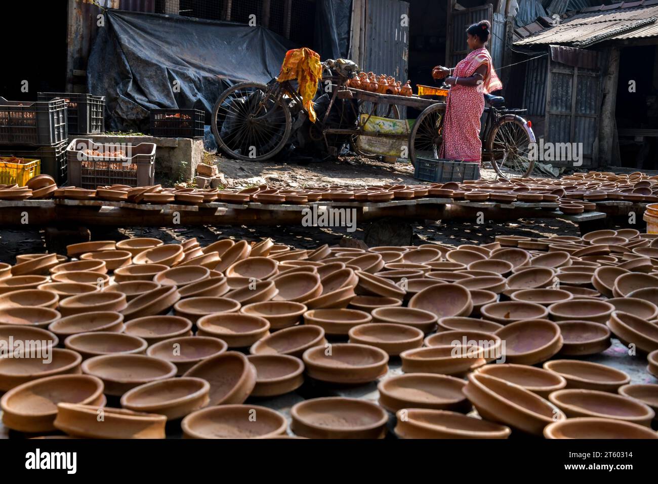Ein Arbeiter färbt eine Erdlampe im Töpferdorf Chaltaberia, rund 40 km von Kalkutta in Westbengalen. Das ganze Dorf ist im vollen Rhythmus der irdenen Lampen- und Idol-Produktion vor dem Diwali-Festival in Indien. Erdlampen werden in allen indischen Städten verkauft, wie Kalkutta, Delhi, Mumbai, Hyderabad, Gujarat, Assam, Patna und Rajasthan, besonders während der Festivalsaison. Sogar Erdlampen werden vor den Diwali-Feiern nach außerhalb Indiens exportiert. Stockfoto