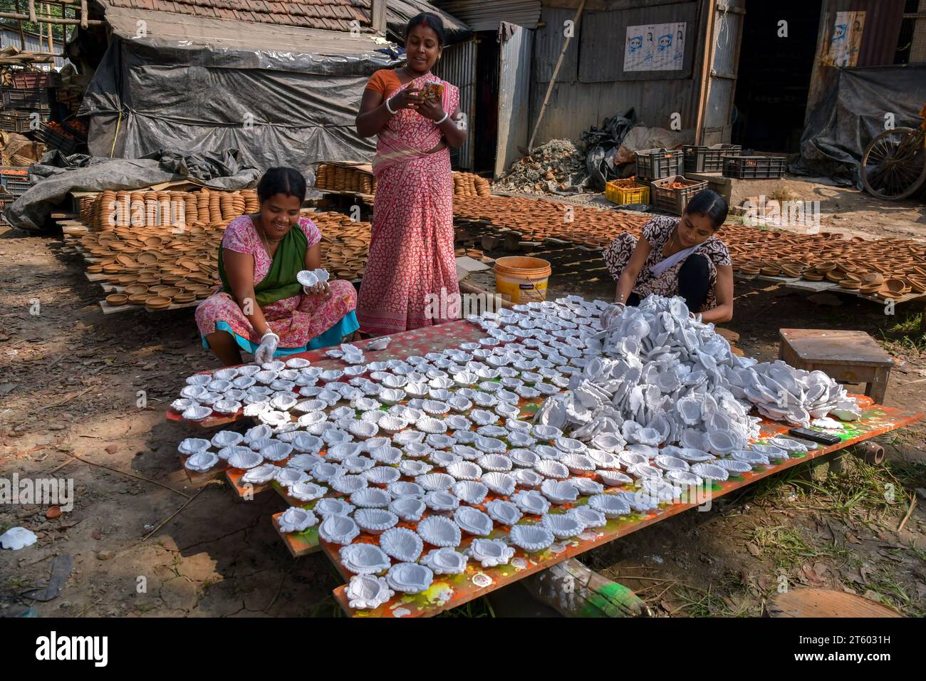 Arbeiterinnen sortieren Erdlampen, bevor sie im Töpferdorf Chaltaberia, etwa 40 km vor Kalkutta in Westbengalen, färben. Das ganze Dorf ist im vollen Rhythmus der irdenen Lampen- und Idol-Produktion vor dem Diwali-Festival in Indien. Erdlampen werden in allen indischen Städten verkauft, wie Kalkutta, Delhi, Mumbai, Hyderabad, Gujarat, Assam, Patna und Rajasthan, besonders während der Festivalsaison. Sogar Erdlampen werden vor den Diwali-Feiern nach außerhalb Indiens exportiert. Stockfoto