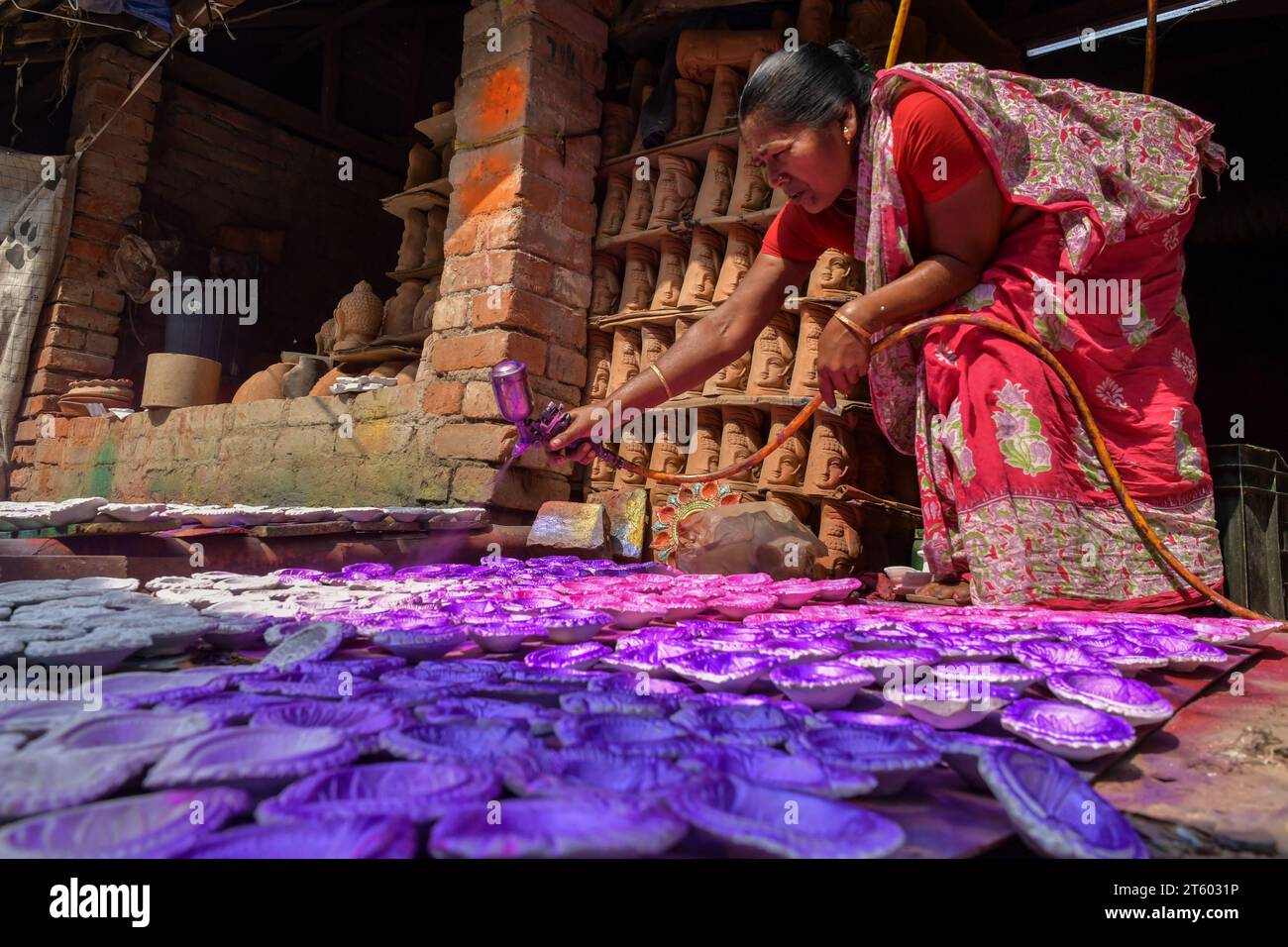 Ein Arbeiter färbt eine Erdlampe im Töpferdorf Chaltaberia, rund 40 km von Kalkutta in Westbengalen. Das ganze Dorf ist im vollen Rhythmus der irdenen Lampen- und Idol-Produktion vor dem Diwali-Festival in Indien. Erdlampen werden in allen indischen Städten verkauft, wie Kalkutta, Delhi, Mumbai, Hyderabad, Gujarat, Assam, Patna und Rajasthan, besonders während der Festivalsaison. Sogar Erdlampen werden vor den Diwali-Feiern nach außerhalb Indiens exportiert. Stockfoto