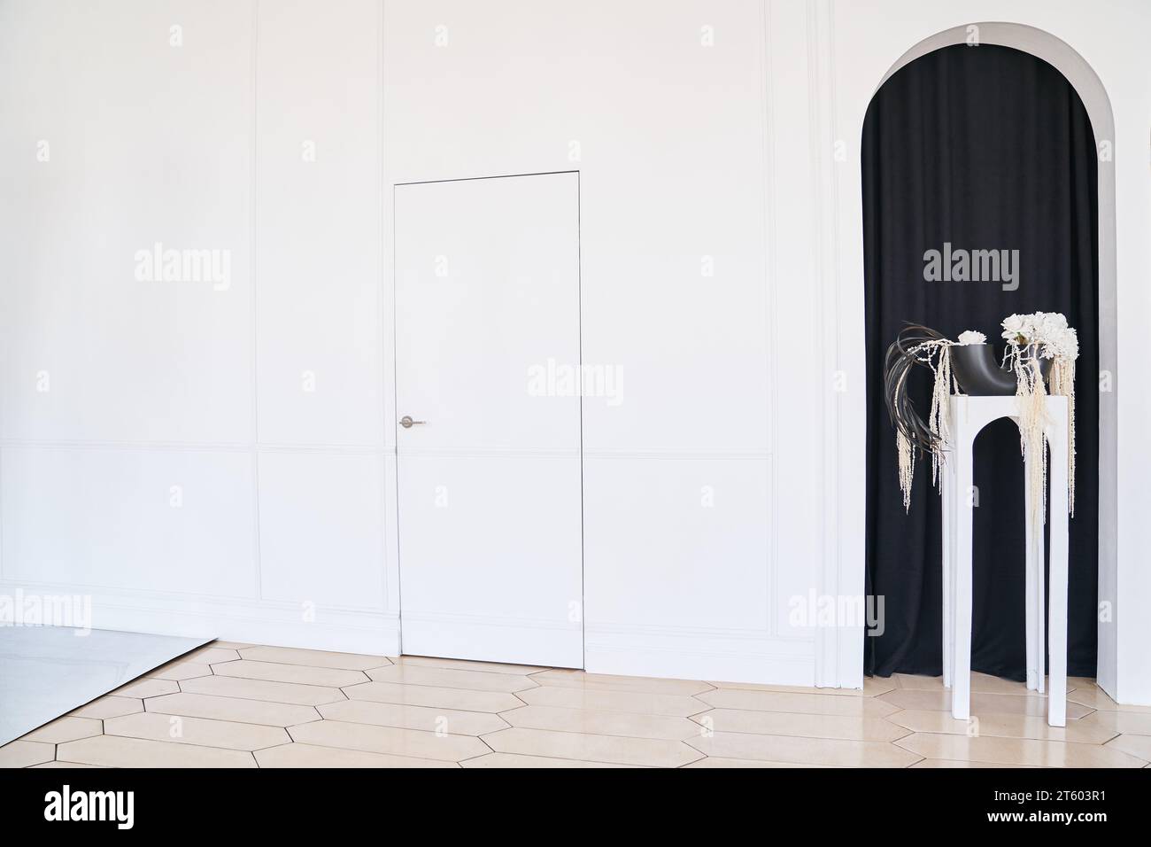 Weiße Holztür auf hellem Hintergrund. Kreative Idee einer geschlossenen Tür, eines Eingangs, neben einem schwarzen Bogen. Innenraumkonzept. Hochwertige Fotos Stockfoto