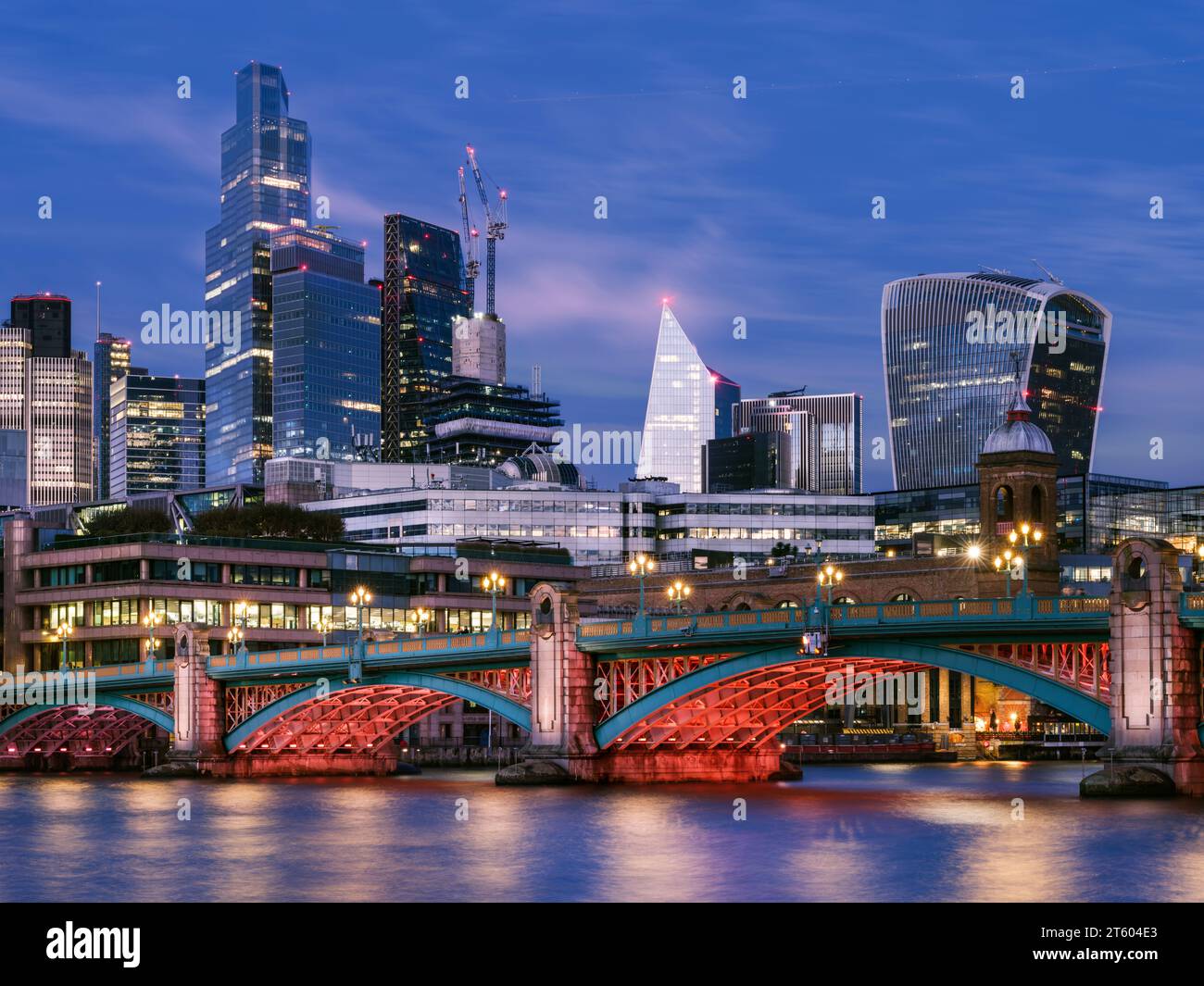 Southwark - London, England. Die Lichter gehen an der Southwark Bridge in der Abenddämmerung an. Überqueren Sie die Themse zwischen Southwark und der Stadt, der bogenförmige B Stockfoto