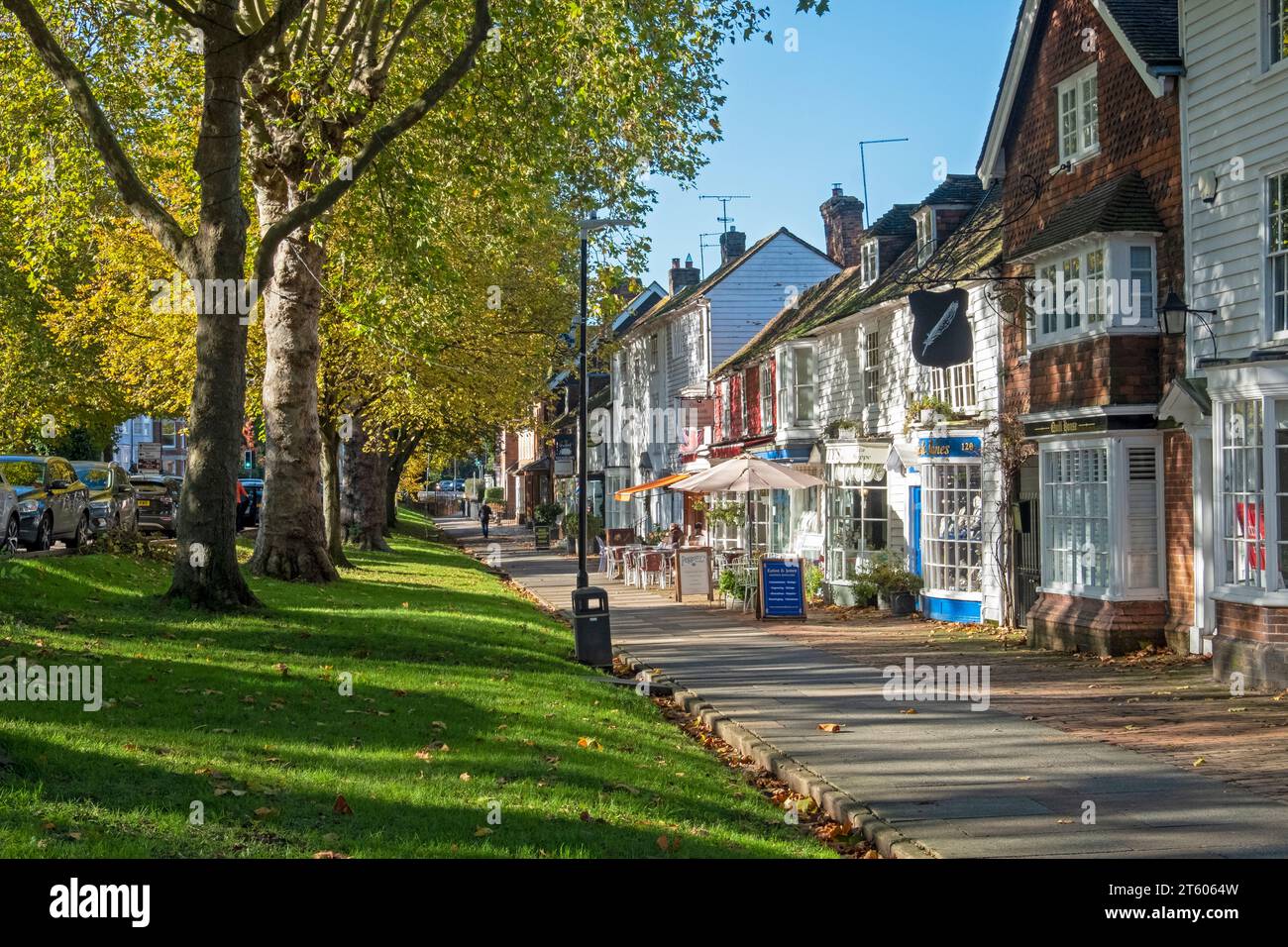 Tenterden High Street, von Bäumen gesäumter breiter Bürgersteig mit Geschäften und Cafés, an einem sonnigen Herbsttag, Kent, Großbritannien Stockfoto