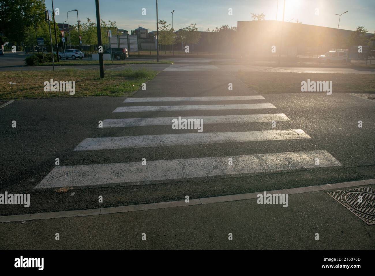 Fußgängerübergänge an der Kreuzung sind immer mit weißen Streifen und Geschwindigkeitsstößen markiert, um die Sicht zu erhöhen. Stockfoto