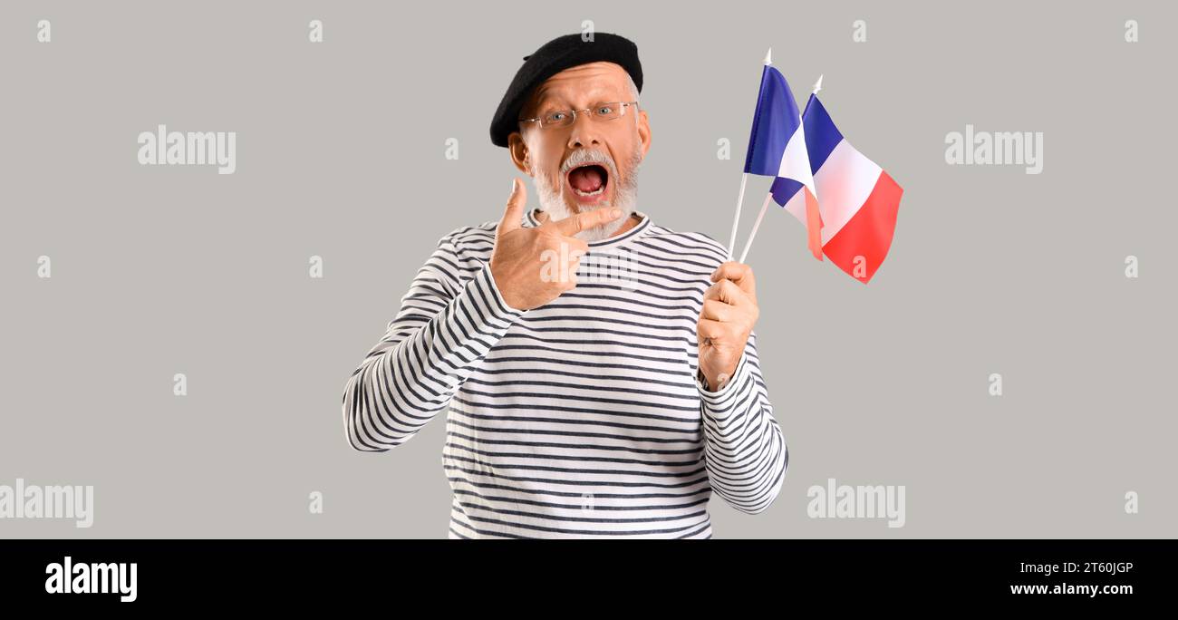 Reifer Mann, der Fahnen von Frankreich auf hellem Hintergrund hält Stockfoto