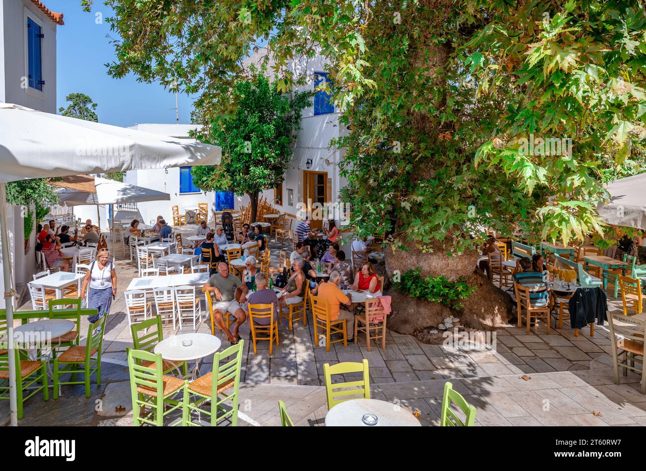 Menschen genießen Erfrischungen im Schatten der alten Platane auf dem Hauptplatz von Pyrgos auf der Insel Tinos, Kykladen, Griechenland. Stockfoto