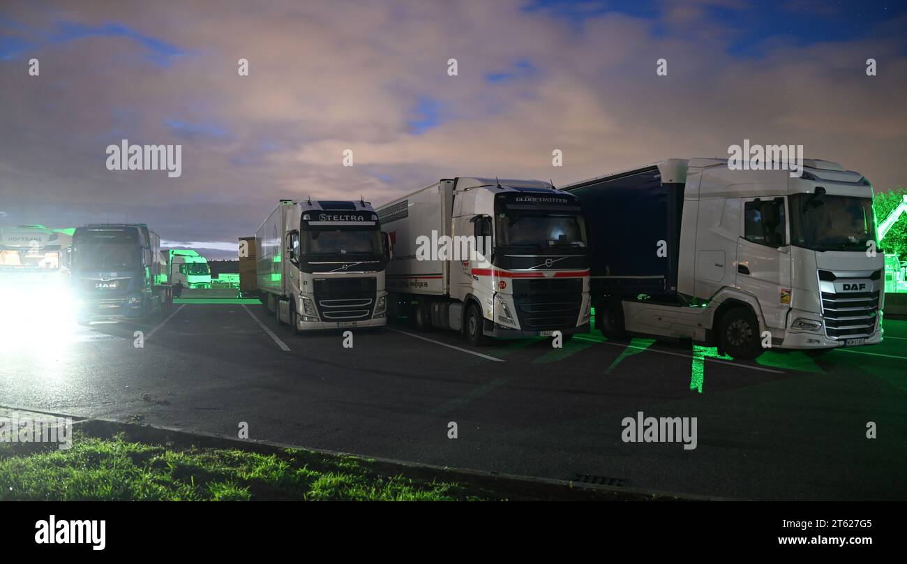 Stuttgart, Deutschland. November 2023. LKWs parkten nachts an einer Servicestelle an der Autobahn 8 bei Denkendorf. Logistikverbände und Lkw-Hersteller sprechen auf einer Pressekonferenz über die Rahmenbedingungen in der Branche. Quelle: Bernd Weißbrod/dpa/Alamy Live News Stockfoto