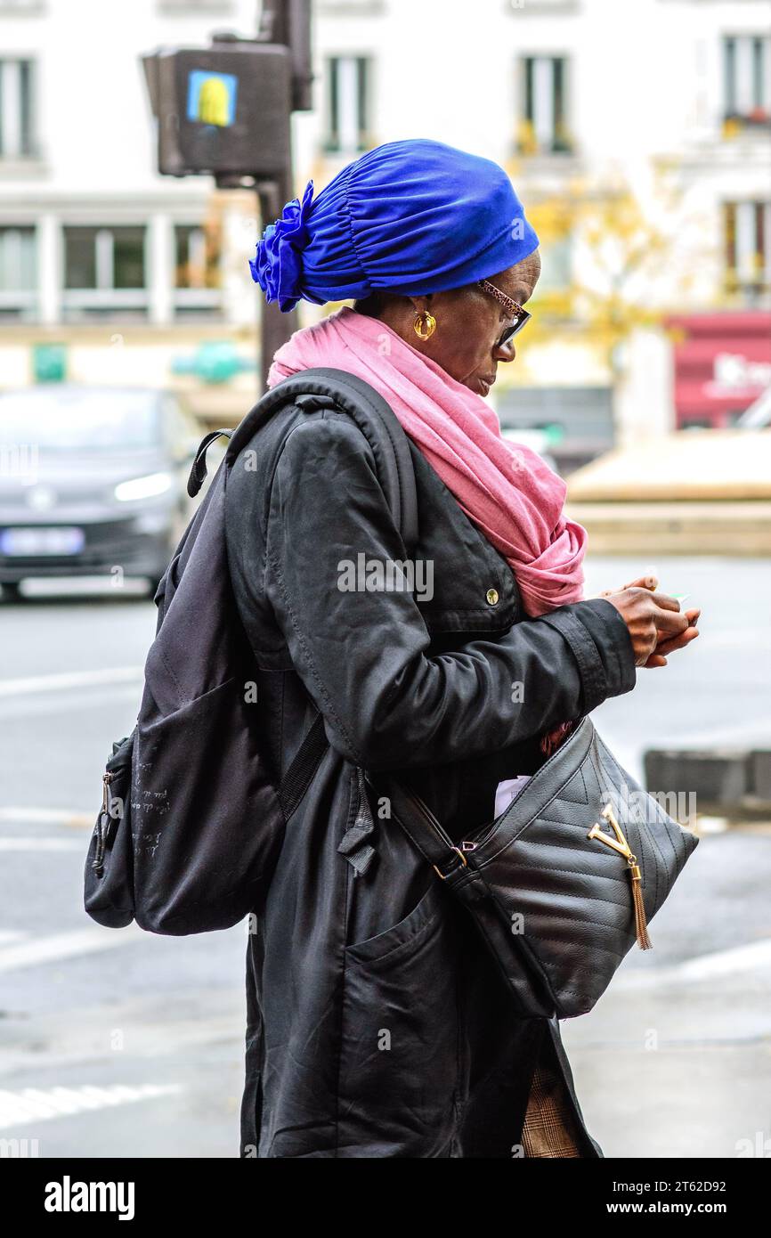 Gut gekleidete schwarze französisch-afrikanische Frau, die Gegenstände in der Hand überprüft - Paris 20, Frankreich. Stockfoto