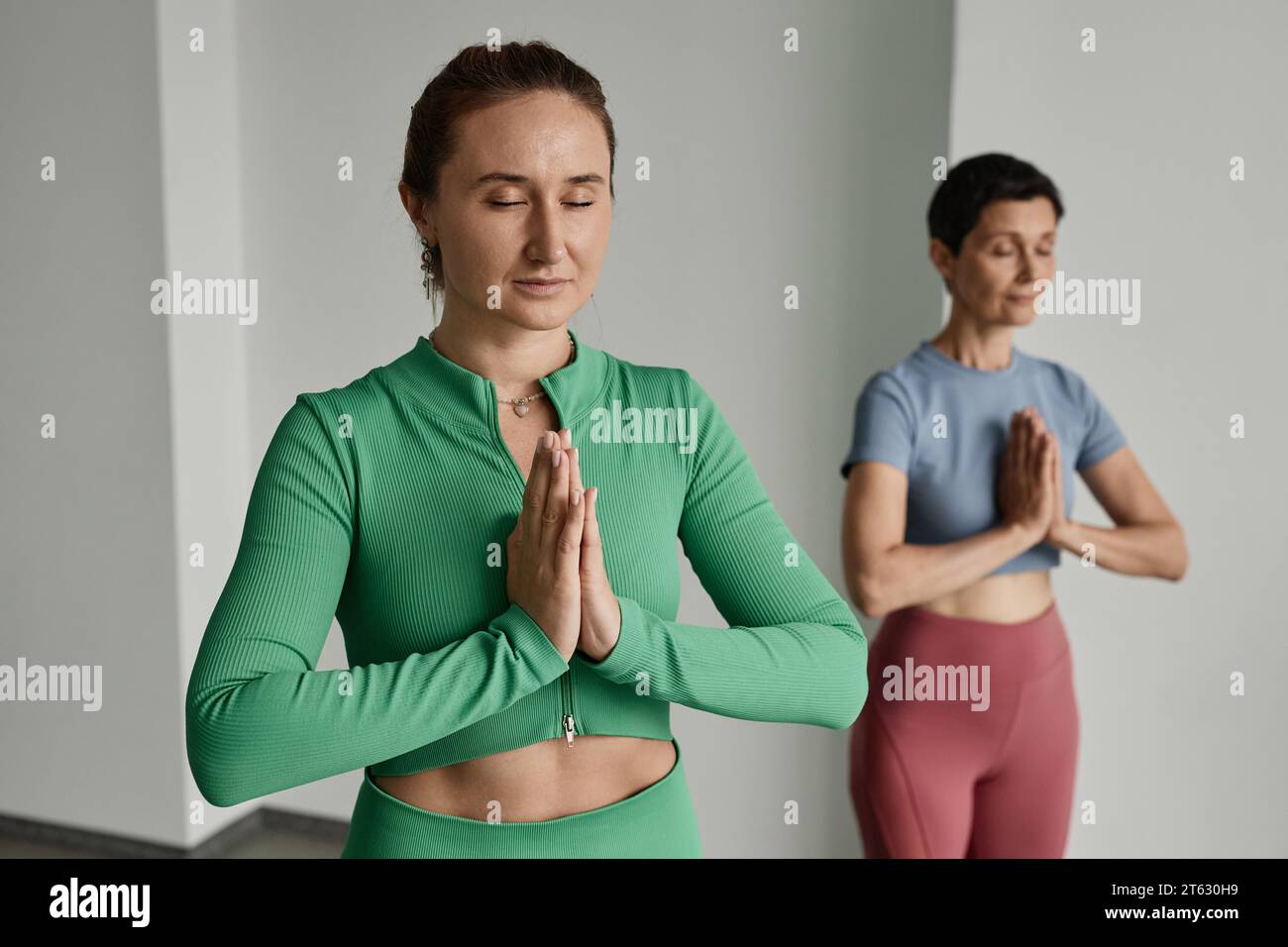 Porträt von zwei jungen Frauen, die mit geschlossenen Augen im Yoga-Studio meditieren, Kopierraum Stockfoto