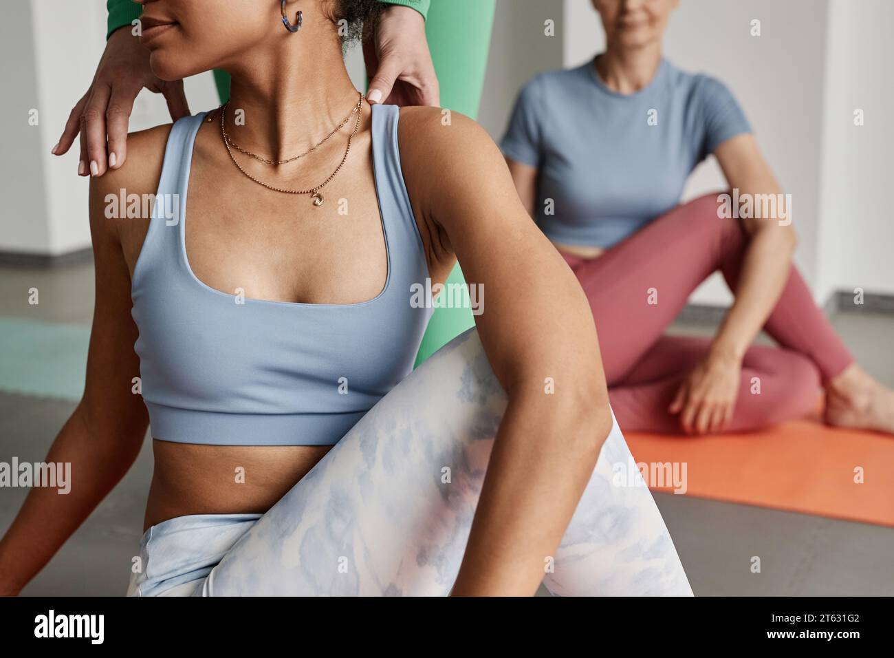 Nahaufnahme einer schwarzen jungen Frau, die Yoga-Twist-Position mit weiblicher Lehrerin macht, Kopierraum Stockfoto