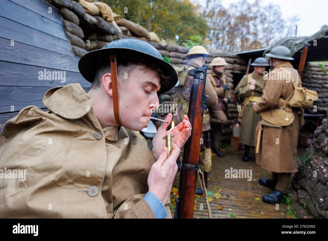 Das Staffordshire Regiment Museum hat Schützengräben gebaut, die den echten aus dem Weltkrieg nachempfunden wurden, um Besuchern ein Erlebnis zu geben, wie das Leben der Soldaten in den Schützengräben war. Das Museum veranstaltet Veranstaltungen mit Reenactoren, um die Stimmung zu schaffen und die Geschichte dieser Zeit zum Leben zu erwecken. Auf dem Bild zündet Isaac Marlow (27) von der Birmingham Pals-Truppe in einem der Gräben eine Zigarette an, die mit einem französischen Feuerzeug aus dieser Zeit aufgerollt wurde. Stockfoto